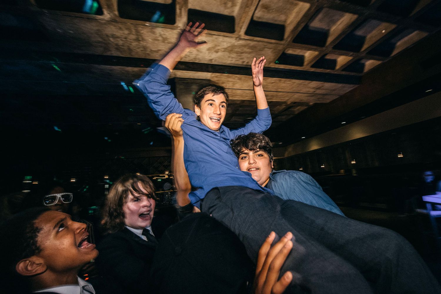 Crowd members lifting and supporting fellow dancers during an energetic party celebration.
