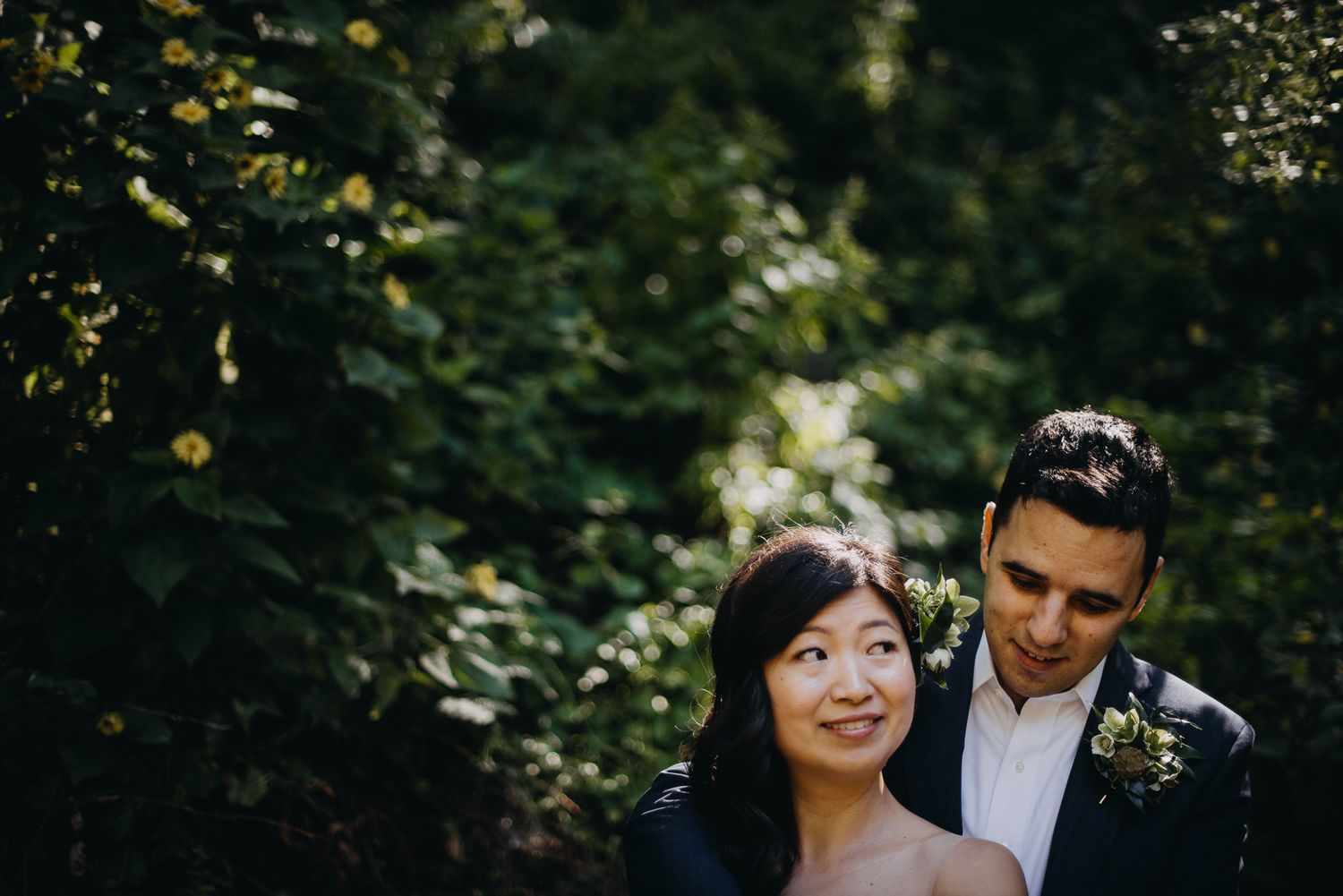 A couple shares an intimate moment together in a lush forest setting during their wedding day.