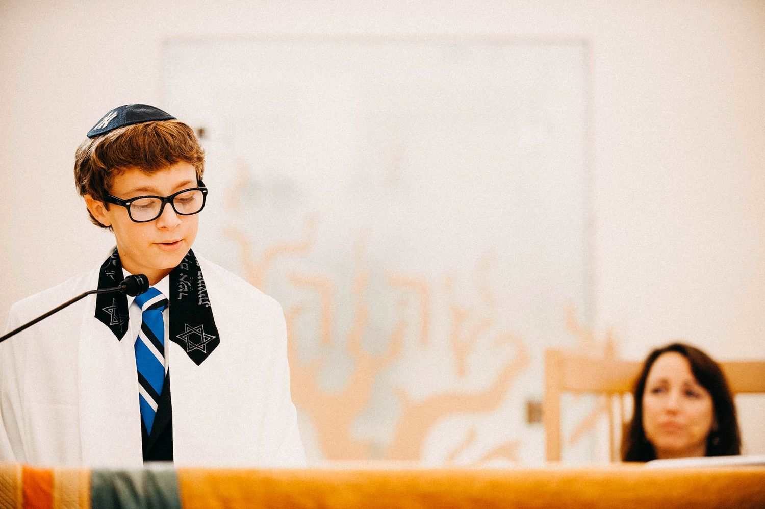 Young speaker in glasses and striped tie stands at podium during formal event.