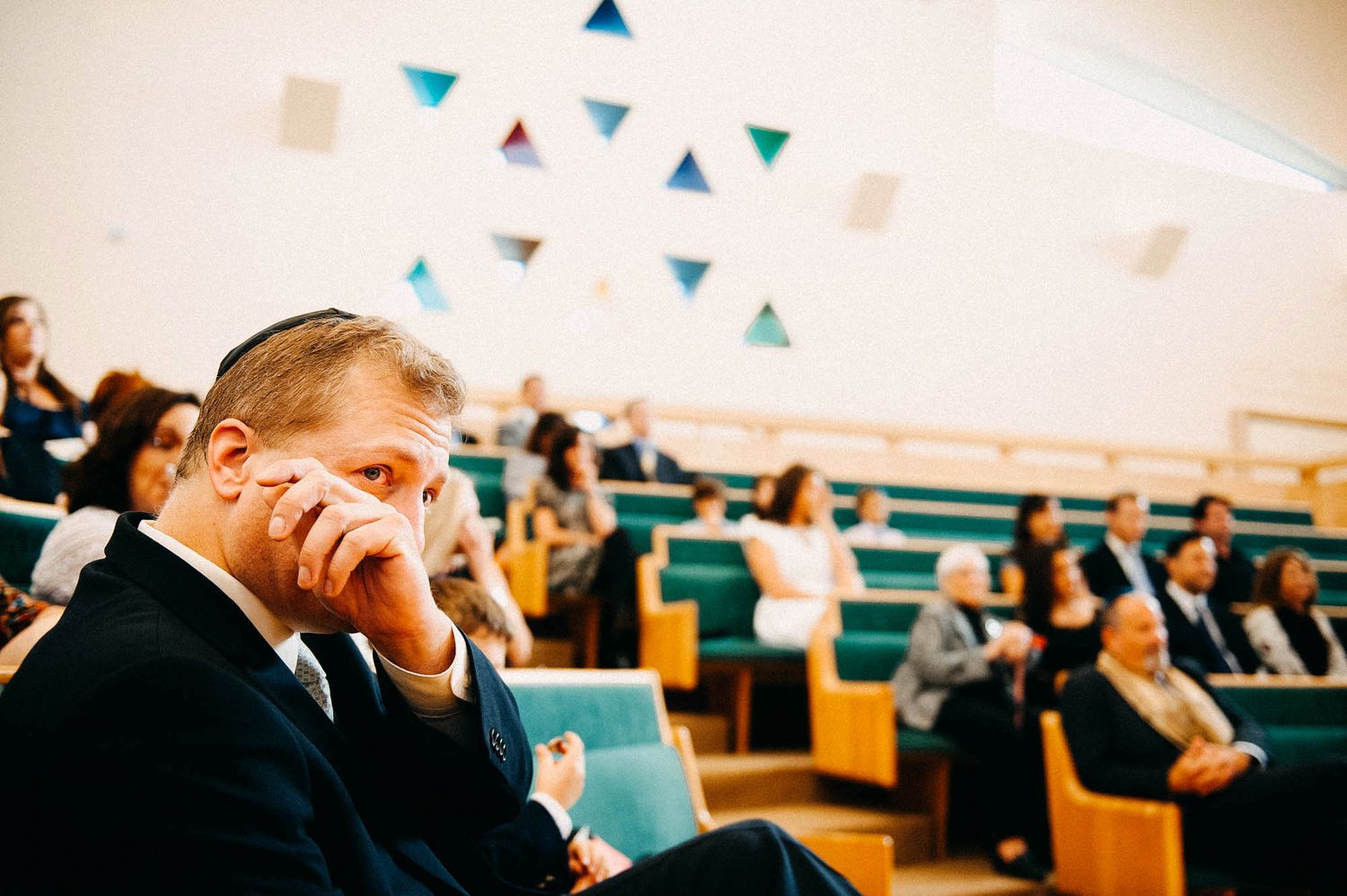 A person in formal attire showing emotion during a ceremony in an auditorium.