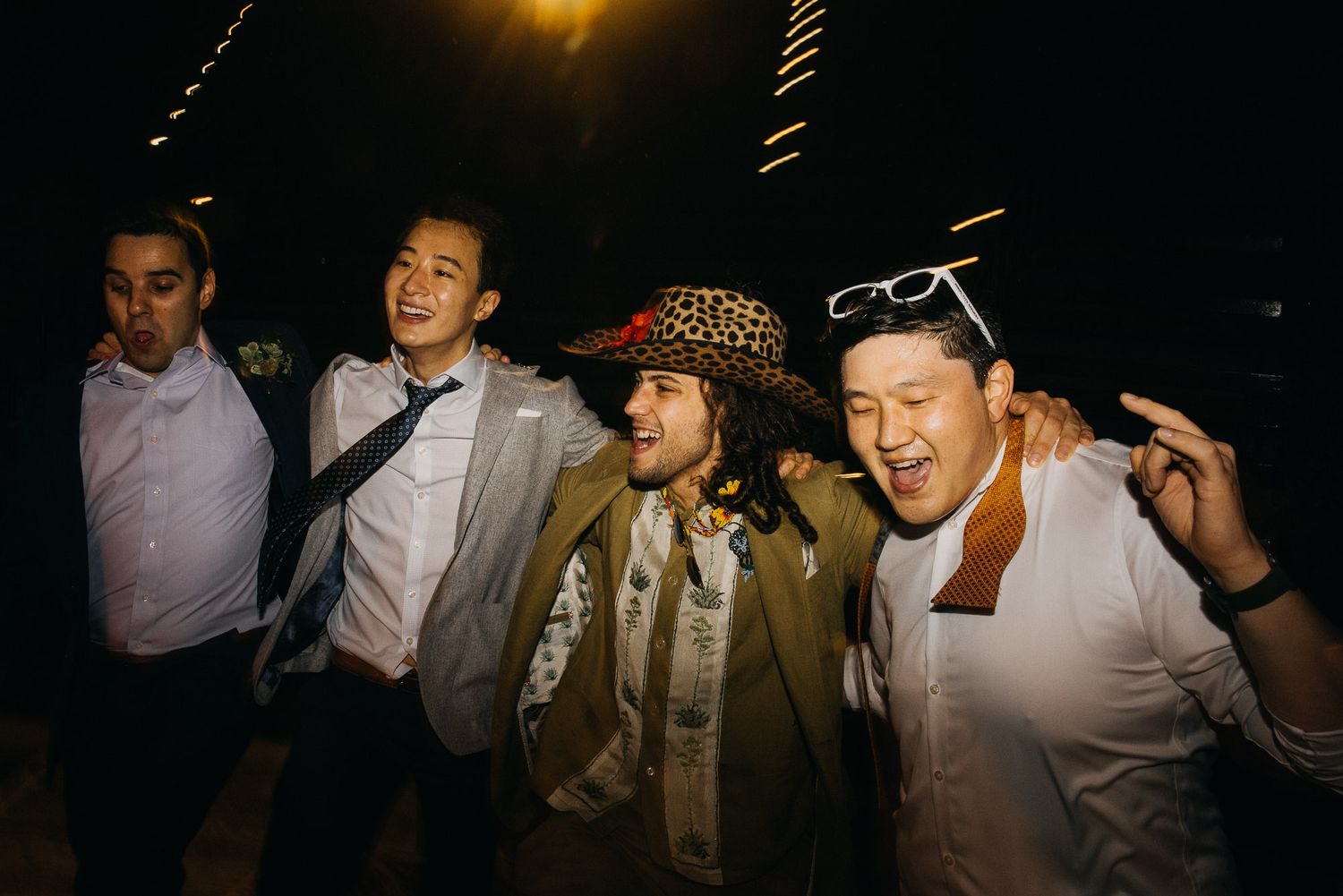 A group of people dancing and celebrating at a lively nighttime party with golden lighting.