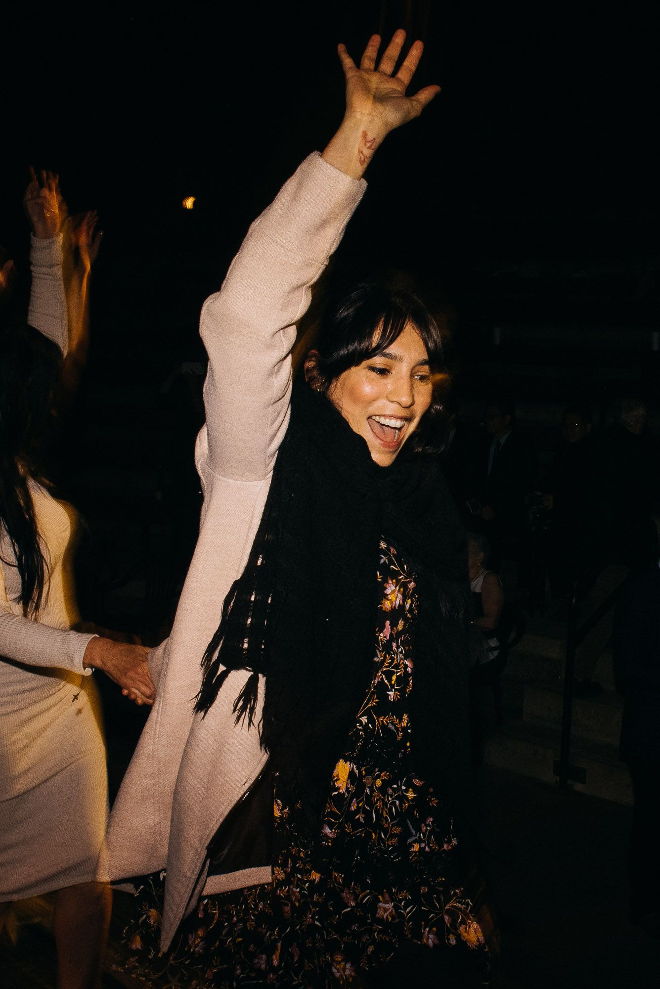 People dancing and raising their hands at a dimly lit party or nightclub with dark atmosphere.