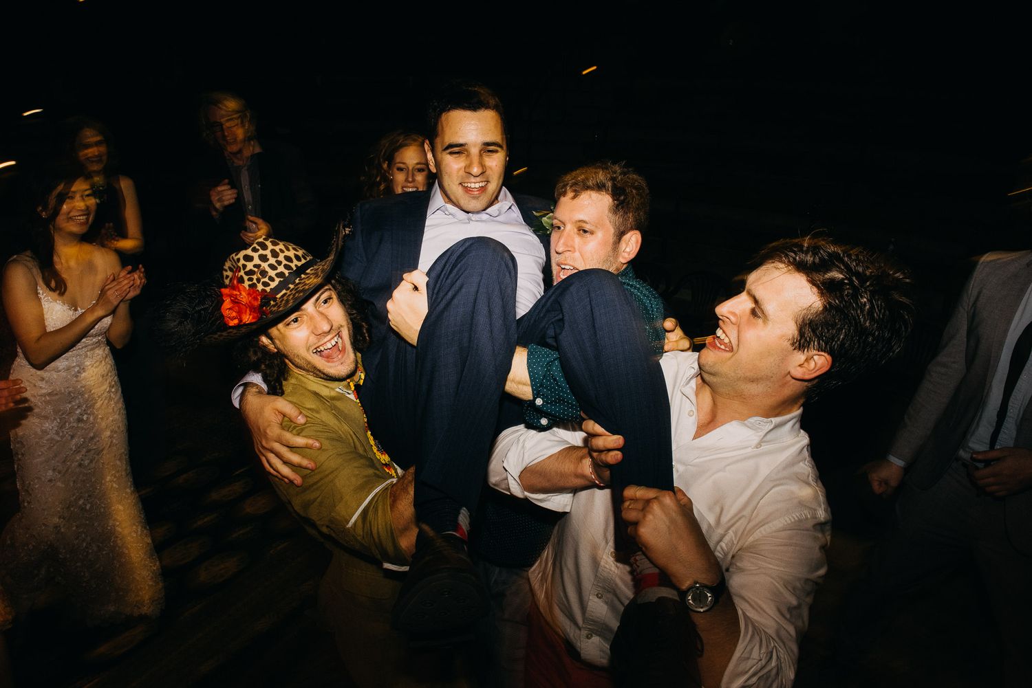 People dancing and celebrating at a lively party in a dimly lit venue.