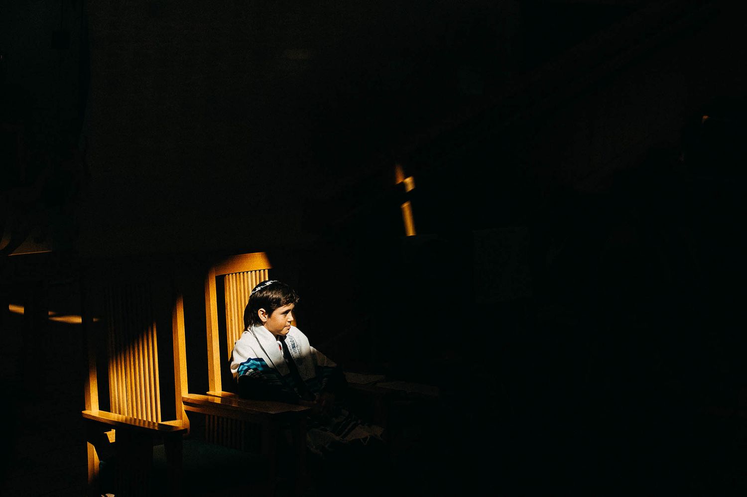 A darkly lit piano performance with dramatic spotlighting illuminating a musician on stage.