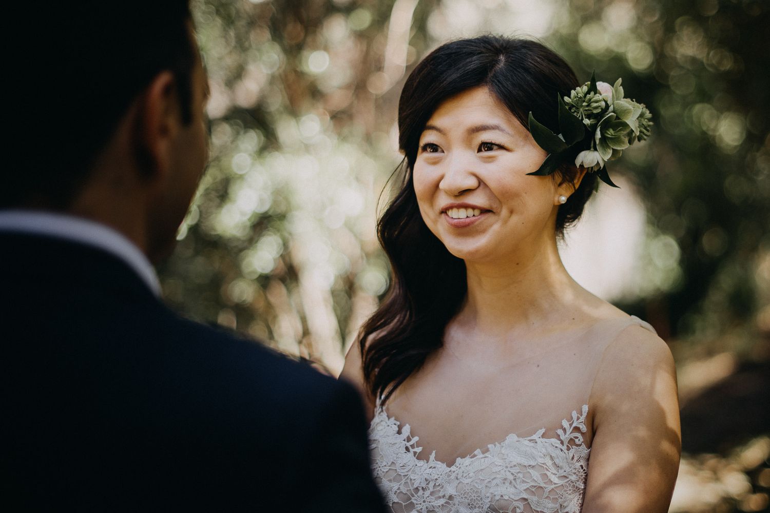 Elegant outdoor wedding ceremony with natural sunlight filtering through trees in a rustic woodland setting.
