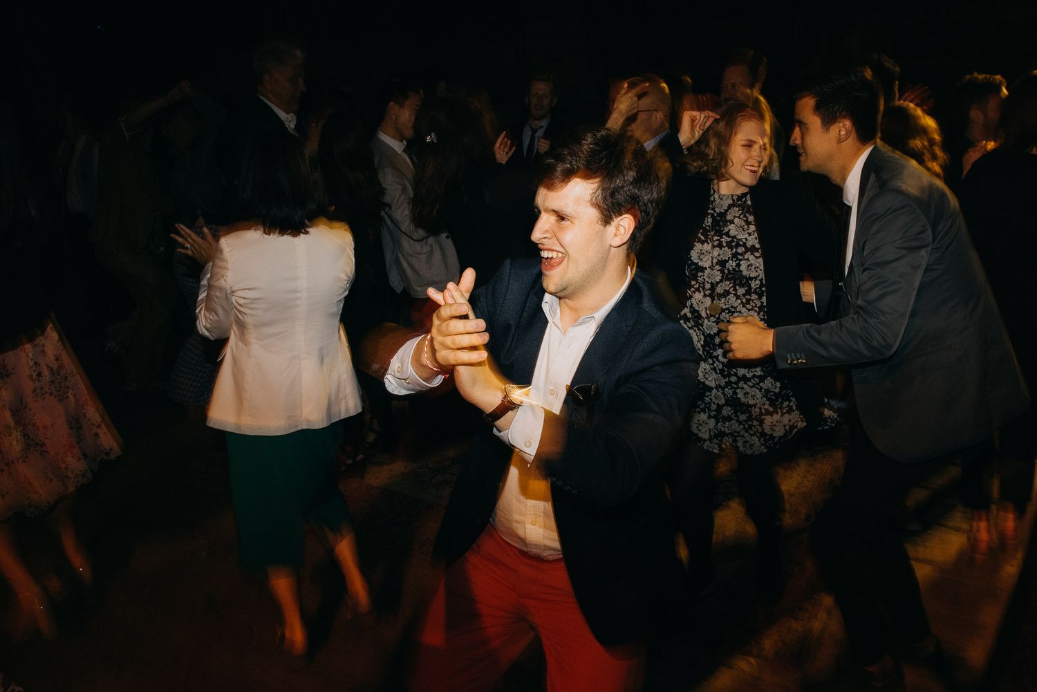 People dancing together at a social gathering in a dimly lit room.