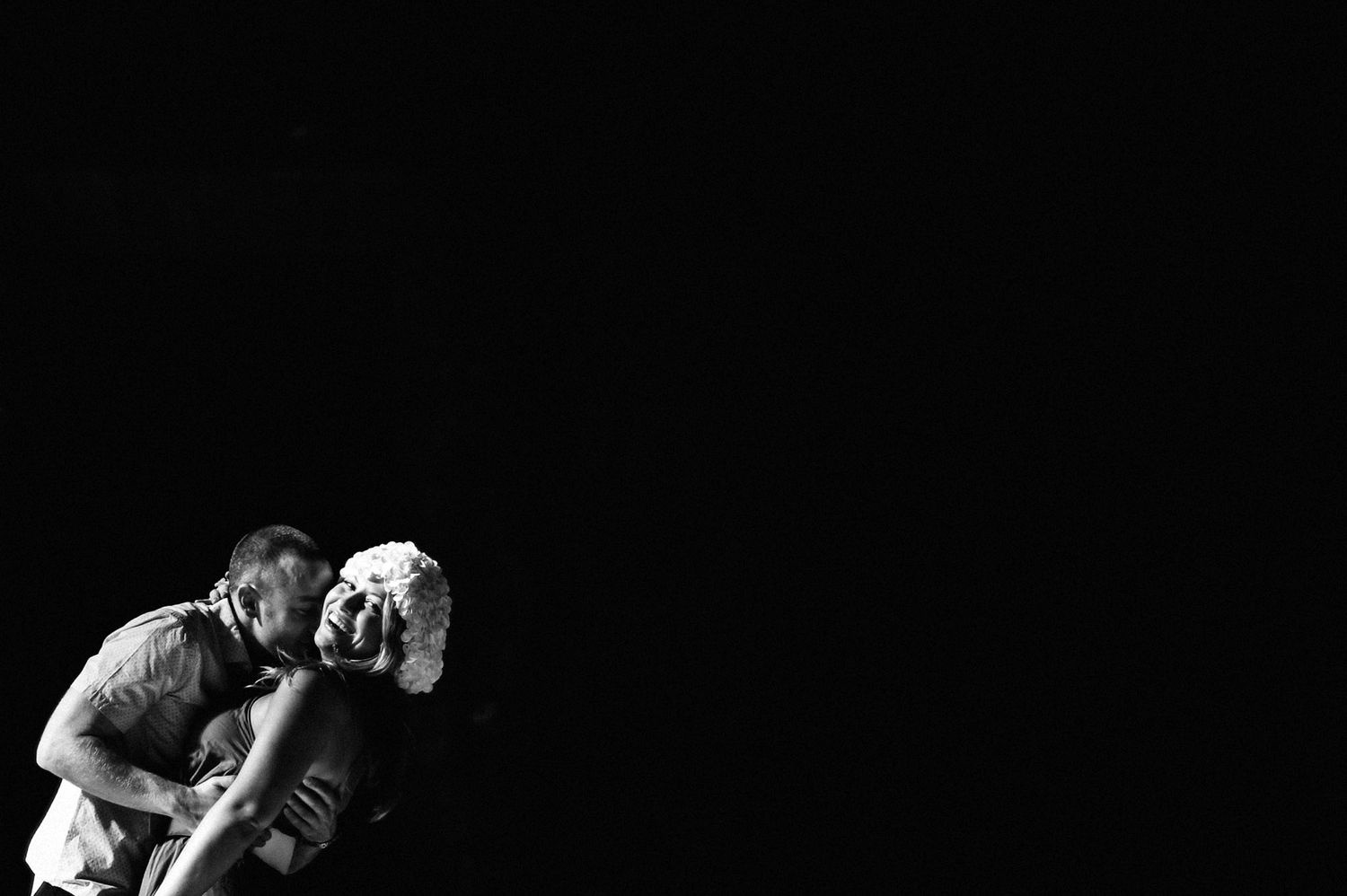 A black and white action photo of a stage performer in motion against a dark background.