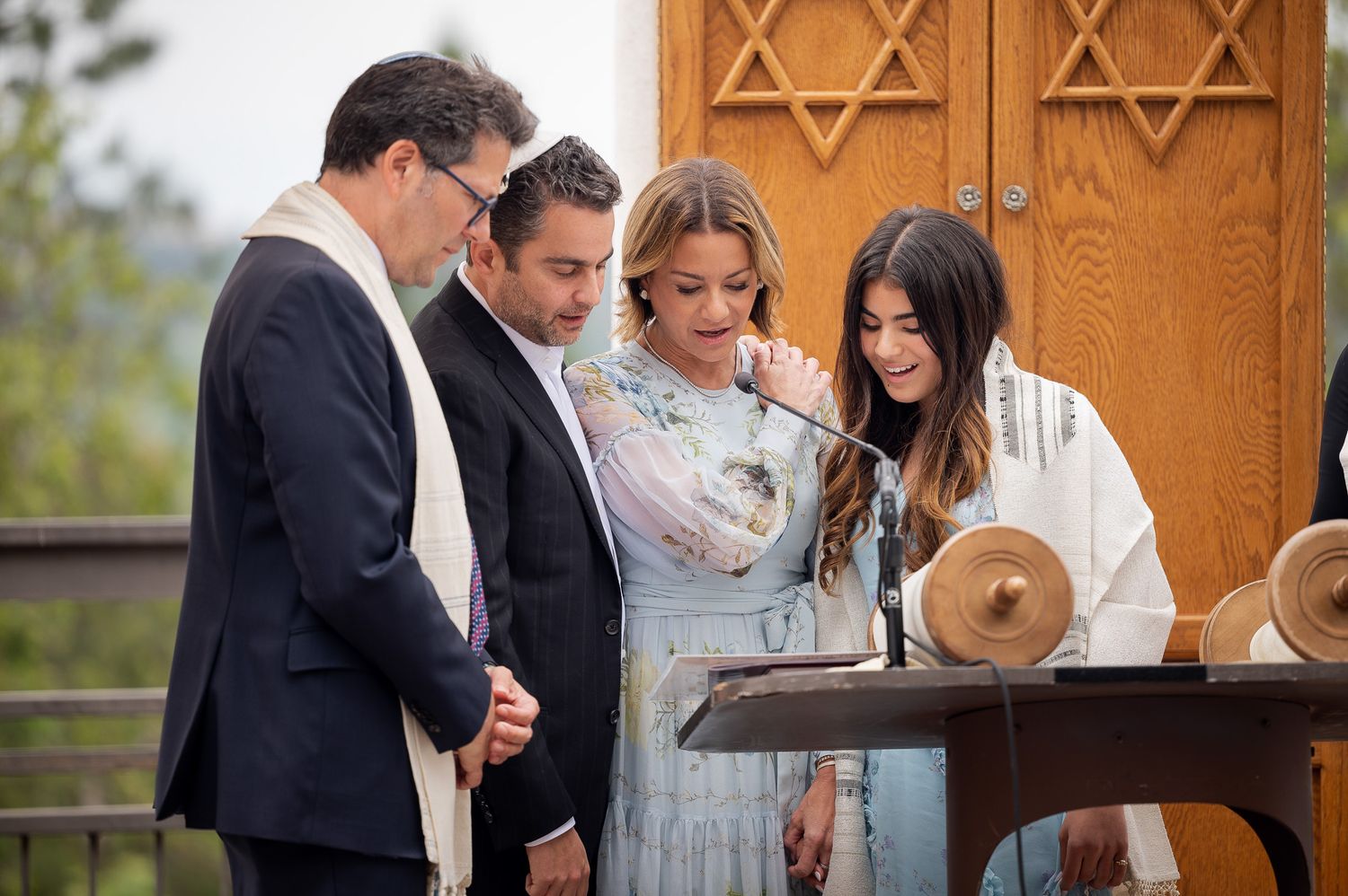 A small group gathers for a traditional Jewish ceremony in front of a wooden door with the Star of David carved into it.