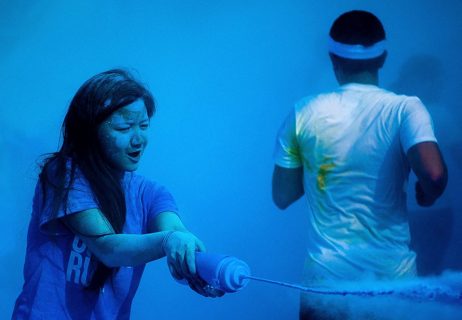 Two people playing an active game with glowing blue lighting and motion effects.