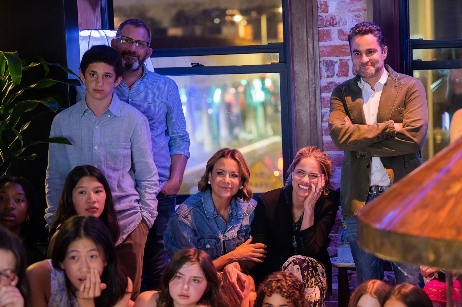 A crowd of spectators watching intently from different levels in an indoor venue during an evening event.