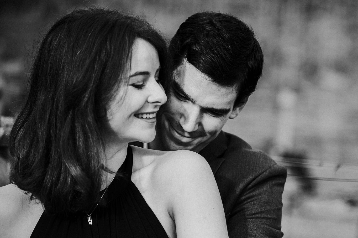 A loving black and white portrait of a couple sharing a romantic and joyful candid moment together.