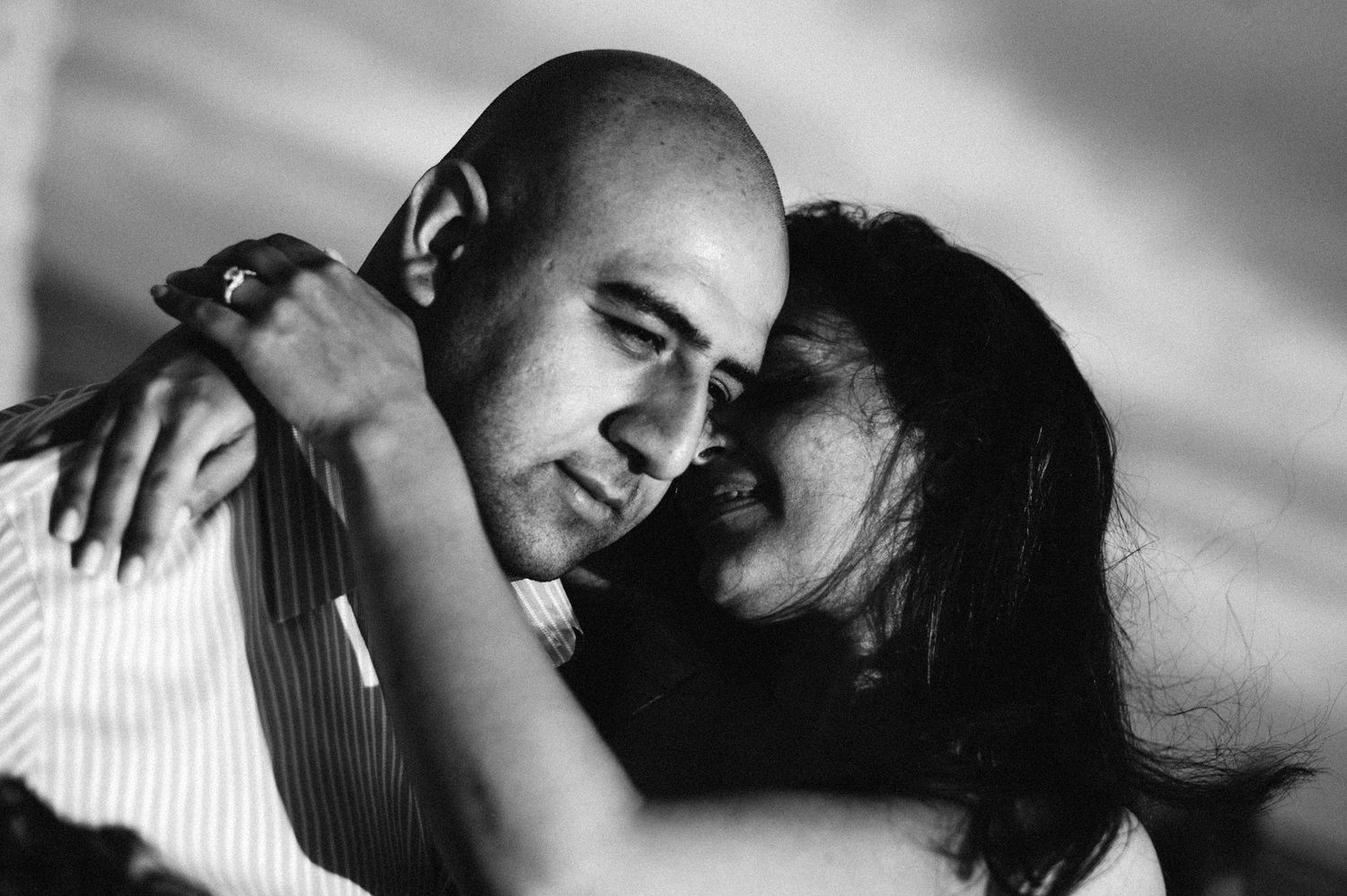 Intimate black and white photograph showing a couple in a tender romantic embrace with dramatic lighting.