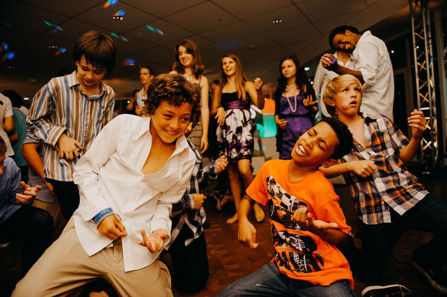 People dancing energetically at a party with colorful lighting and a lively atmosphere.