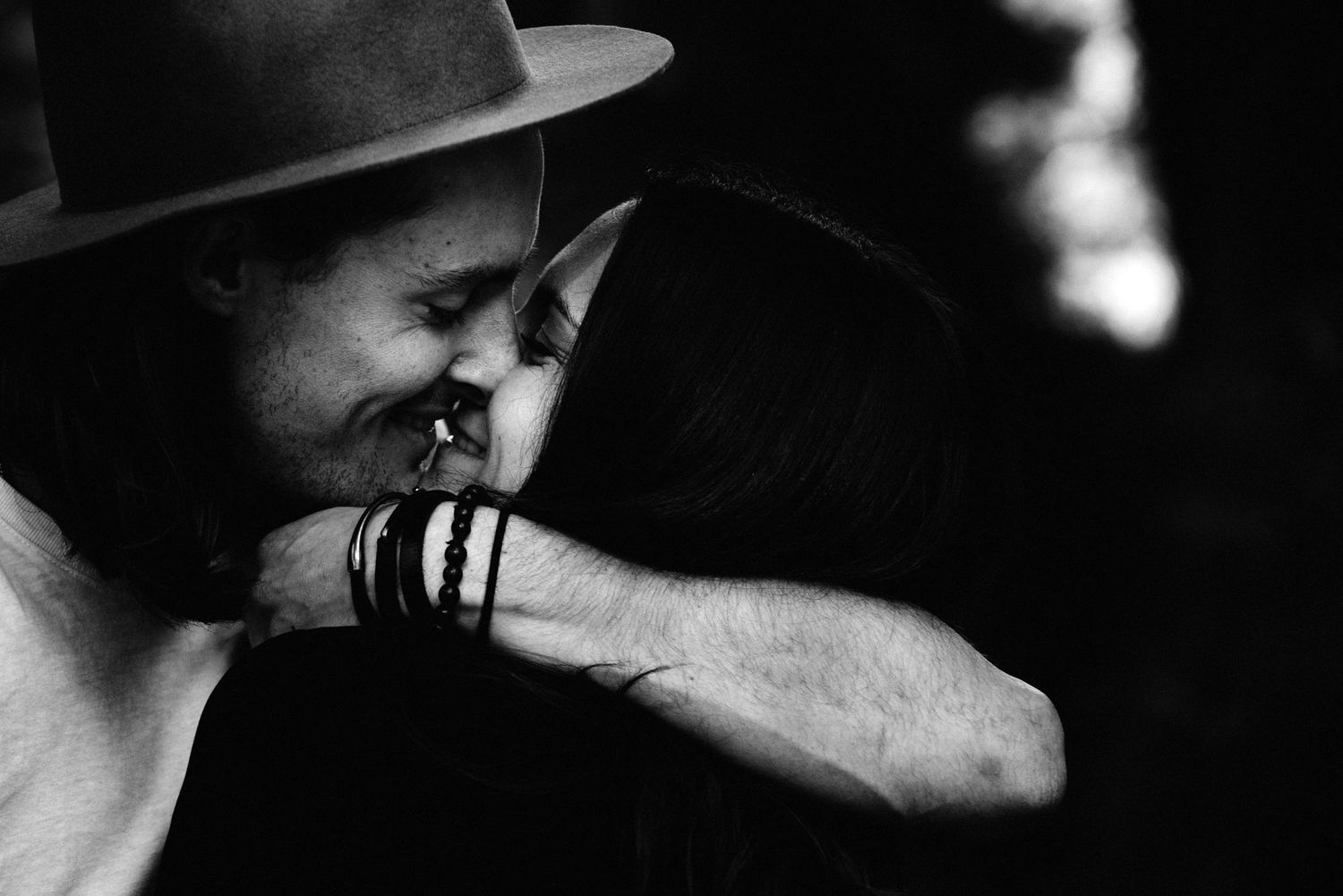 A monochrome photograph captures an intimate moment of tenderness and laughter in dramatic lighting and shadow.