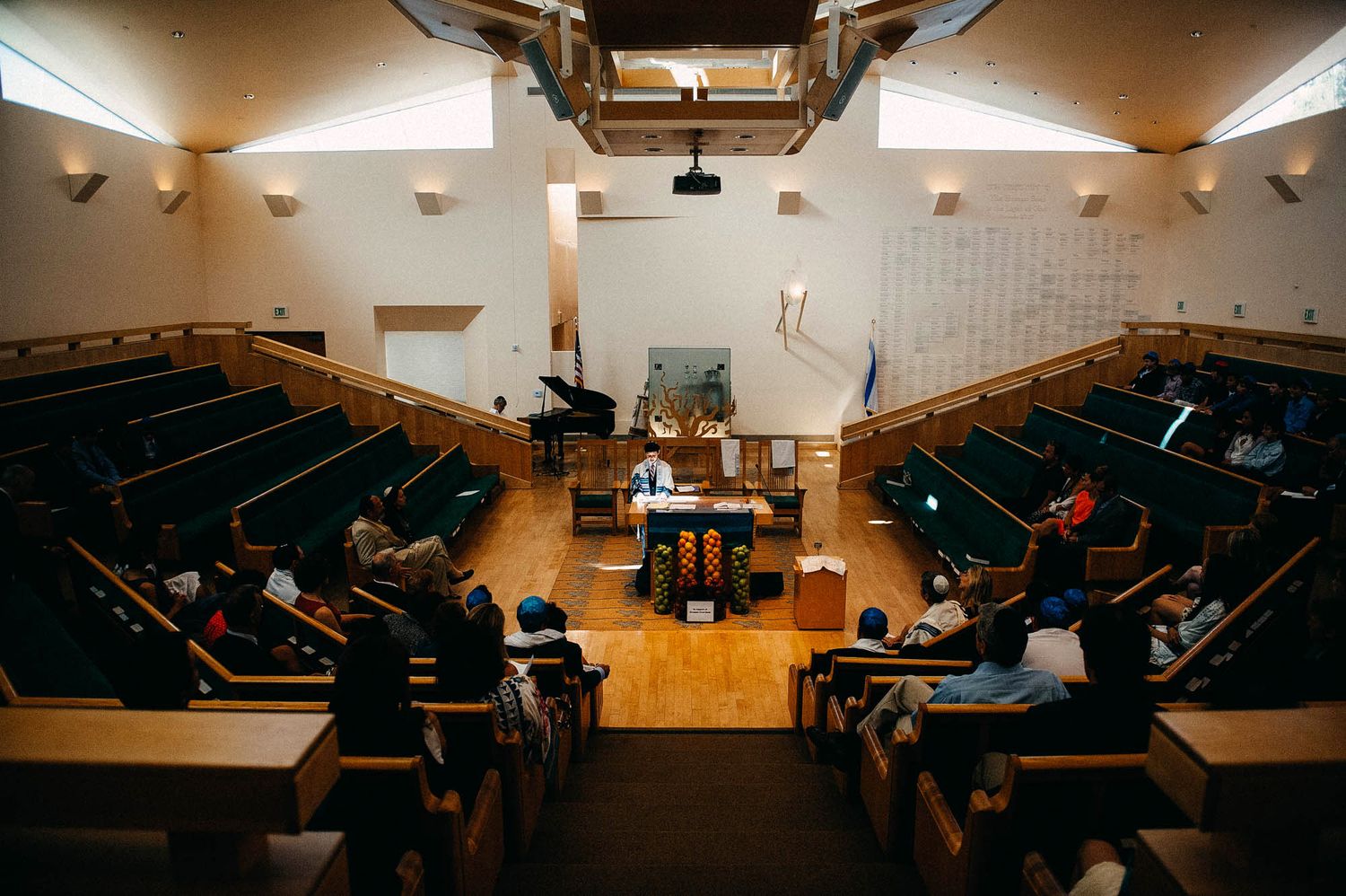 An auditorium with tiered seating and a grand piano on stage under spotlights.