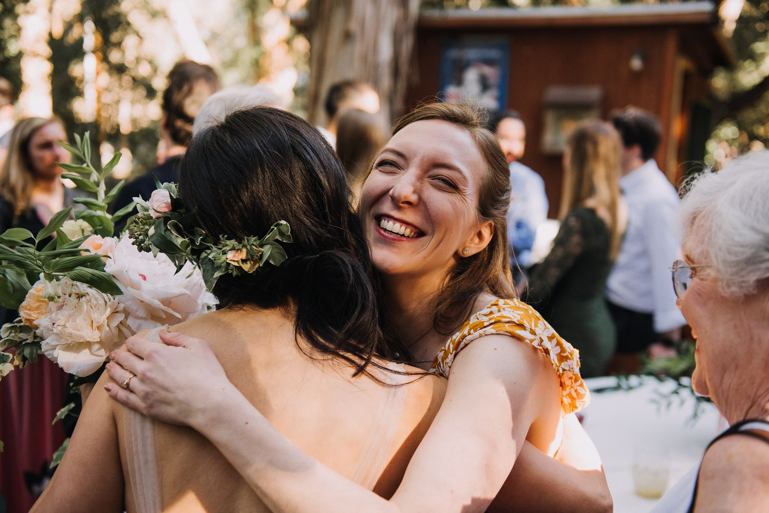 Happy wedding guests embrace and share joyful moments during an outdoor celebration at sunset.