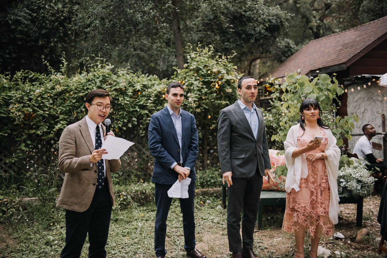 Wedding guests mingle and socialize during an outdoor garden reception on a sunny afternoon.