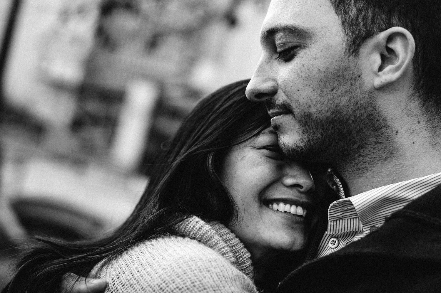 Black and white intimate portrait of a couple sharing a tender moment as they embrace and smile together.