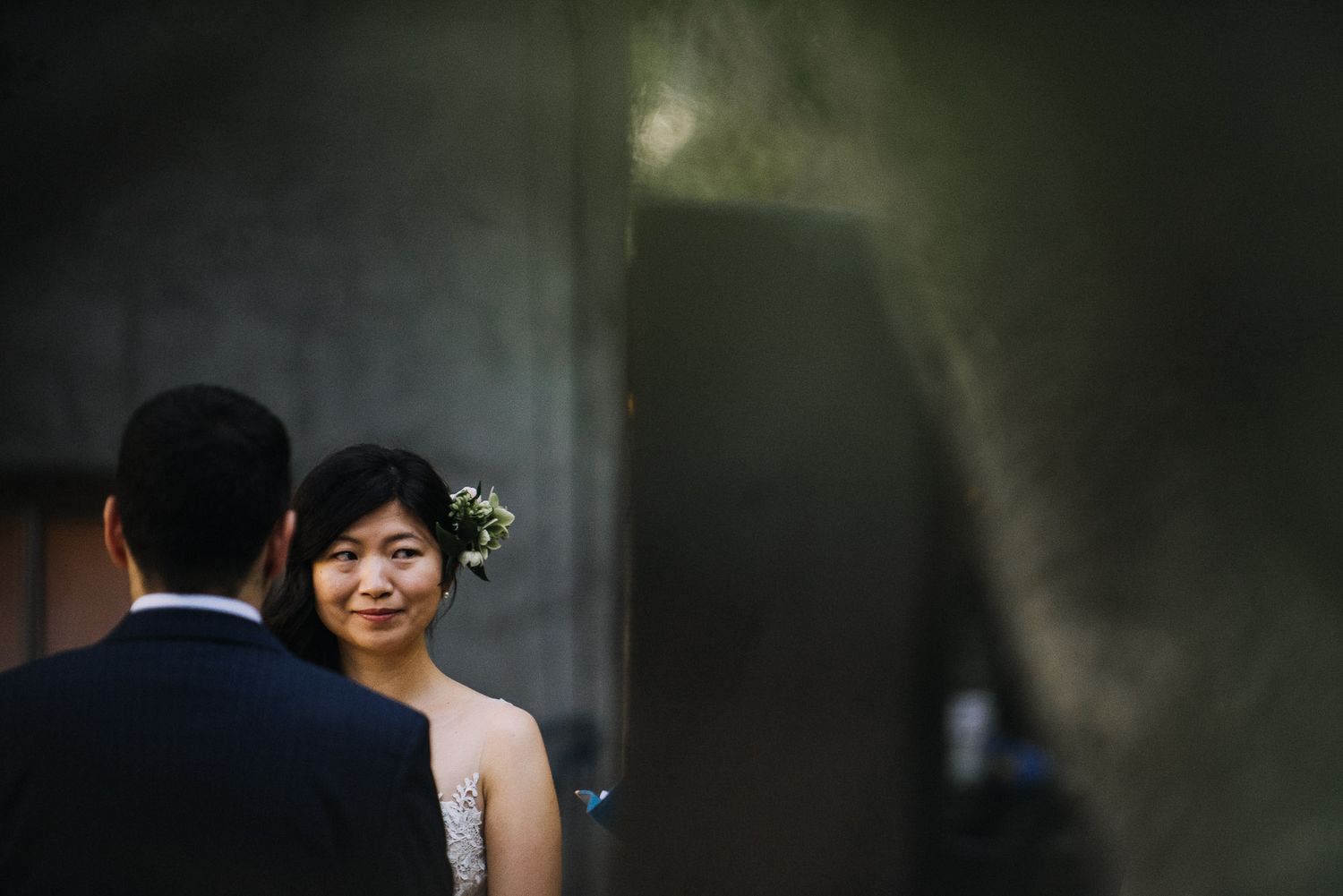 A bride and groom share an intimate moment during their wedding ceremony in a dimly lit setting.