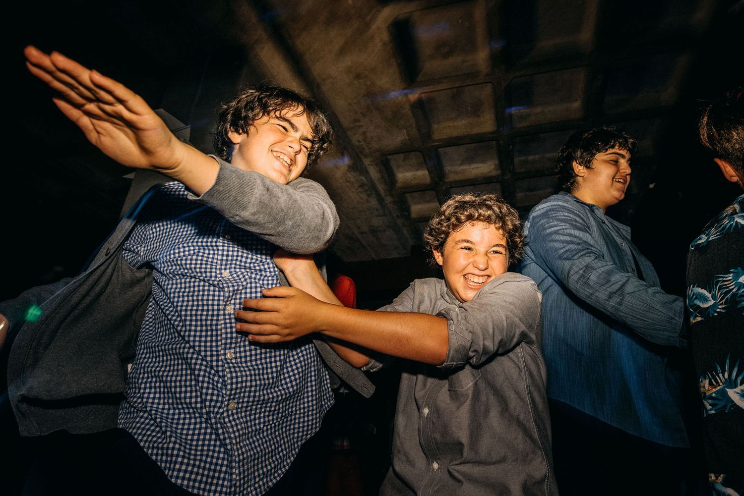 Two people playfully wrestling or dancing together at an indoor venue with dark lighting and stone walls.
