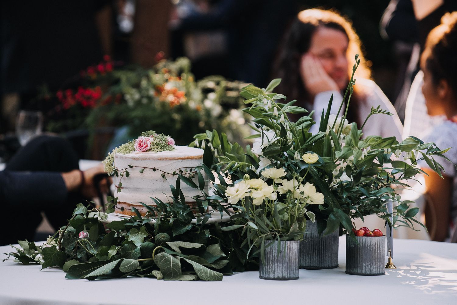 Elegant wedding table centerpiece with greenery and white flowers arranged along a rustic wooden table.