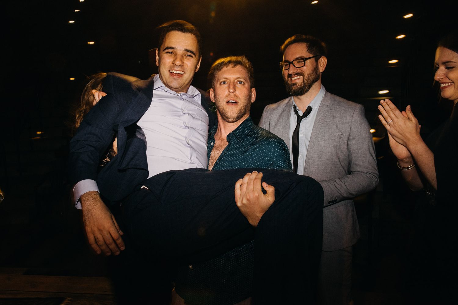 A group of friends having fun and making silly expressions at a dimly lit party or event.