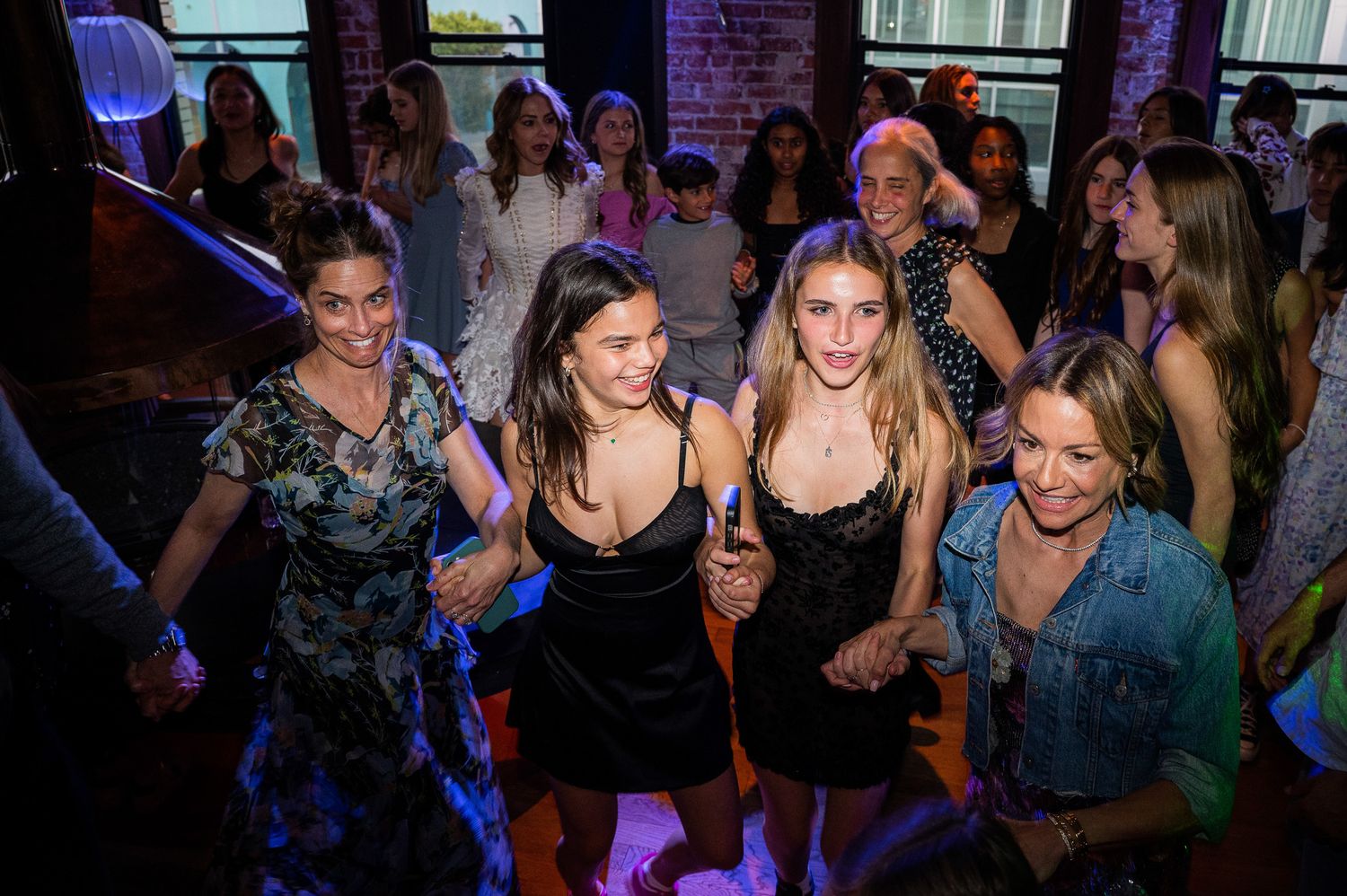 A group of party-goers dancing and having fun in a dimly lit nightclub with blue lighting.