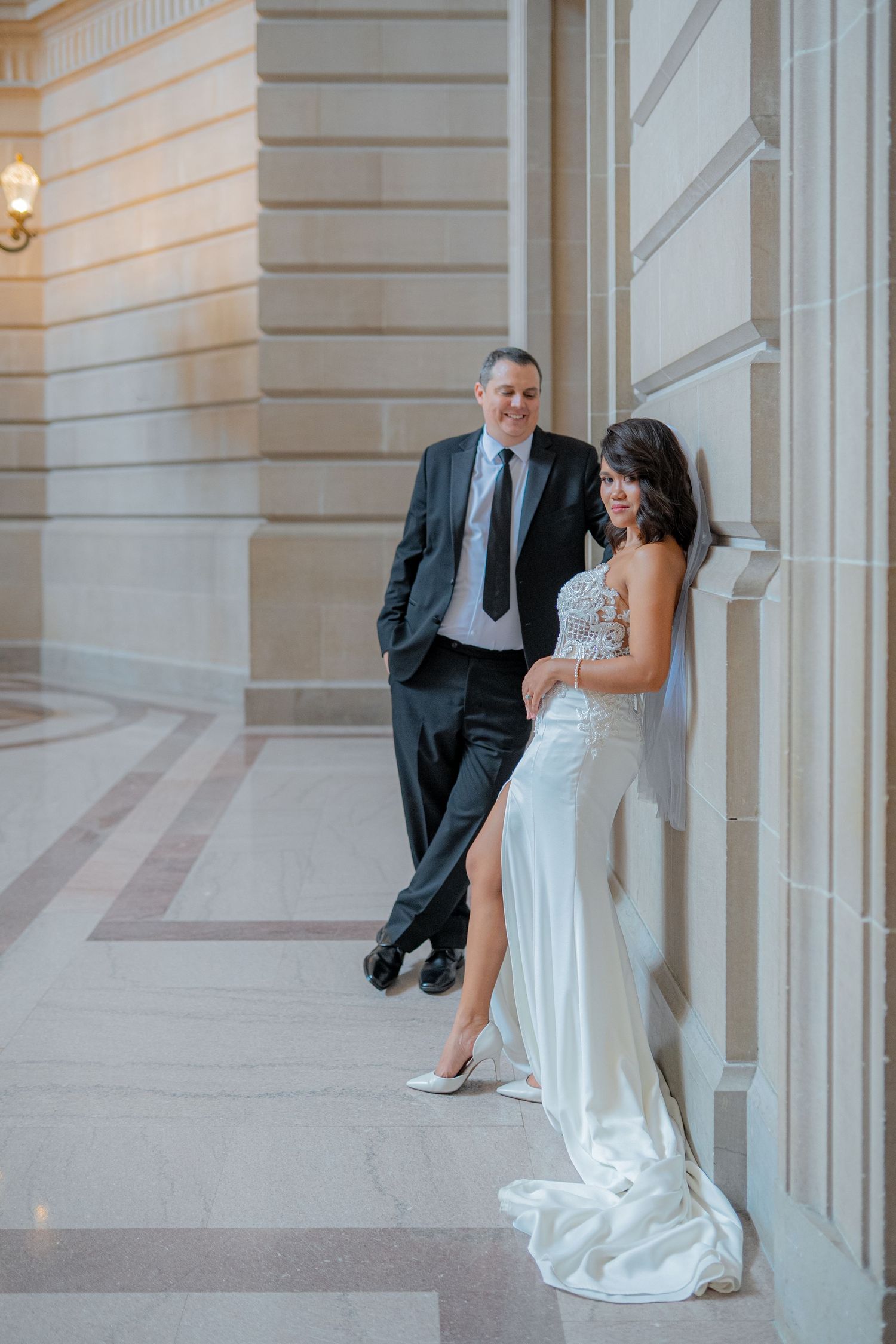 A bride and groom pose together in a sequence of elegant photos along a light-colored columned hallway.