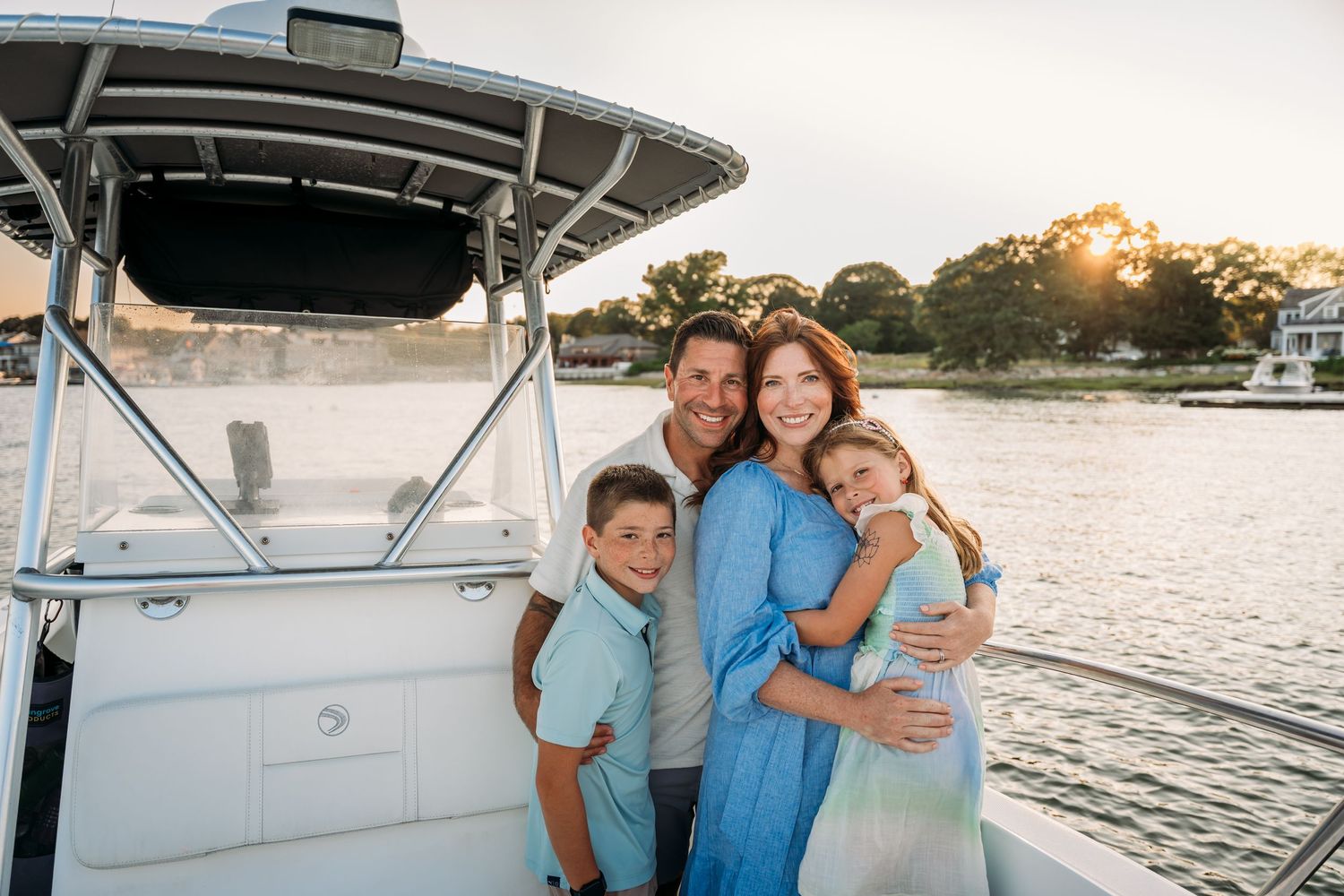 Group enjoying a sunset boat trip along calm waters with scenic coastal views in the background.