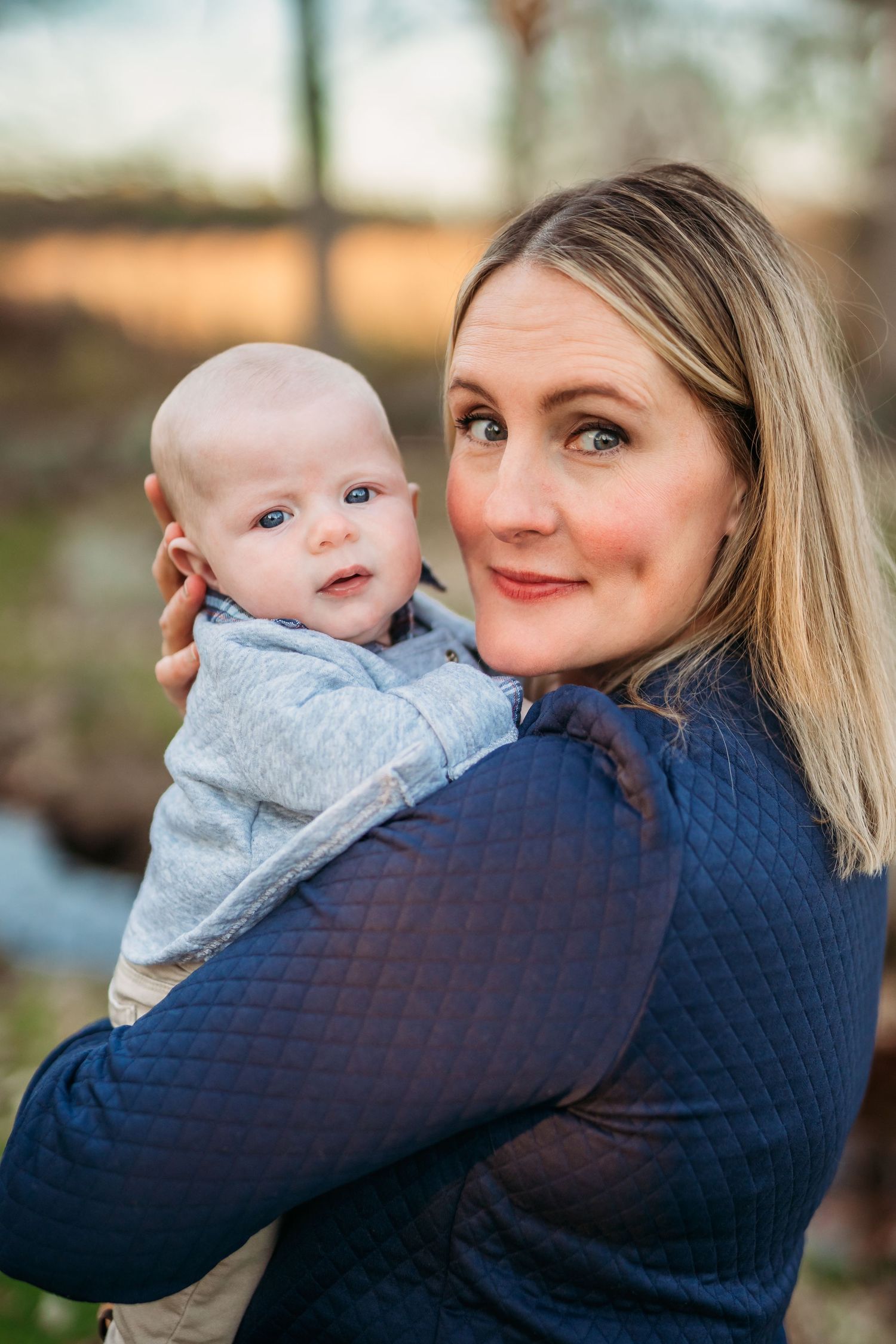 A series of five connected photos showing tender moments between a parent and baby in matching blue outfits outdoors.