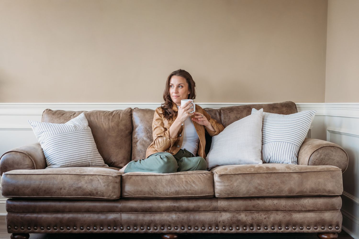 A person relaxes on a comfortable gray couch with throw pillows in a bright, modern living room.