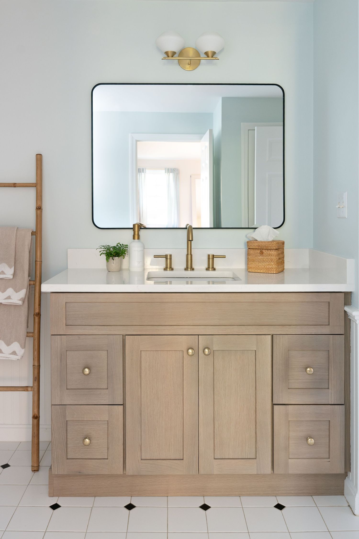Modern floating bathroom vanity with light wood cabinets and white countertop features sleek hardware and built-in storage.