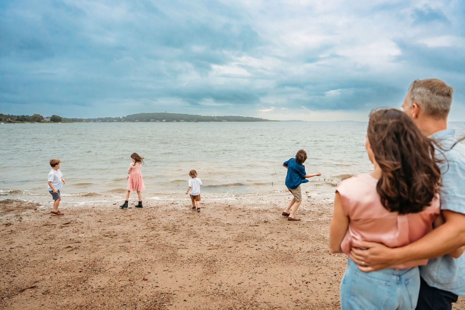 A series of panoramic beach scenes showing people walking along the shoreline on a cloudy summer day.