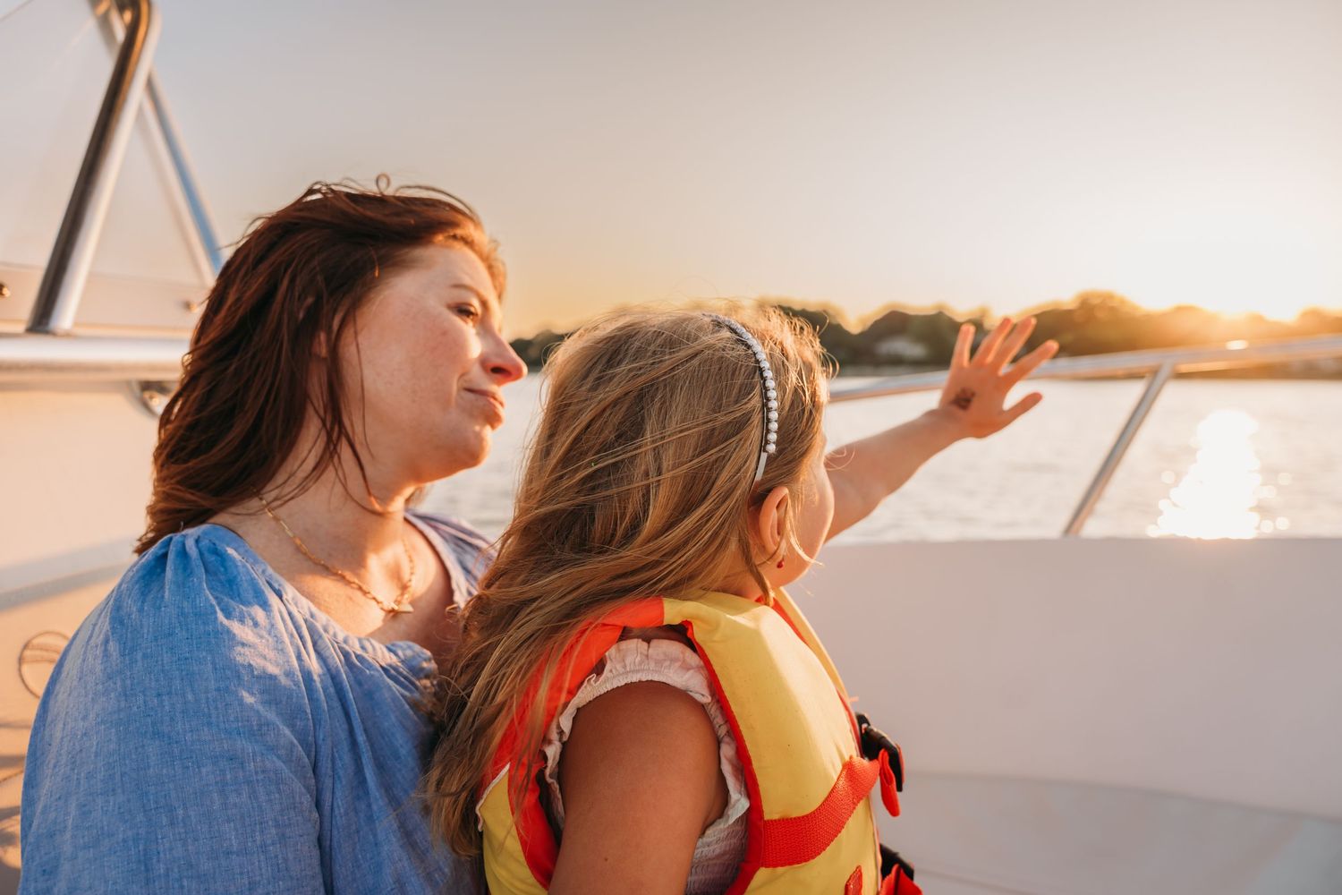 Two people share an intimate moment on a boat at sunset while sailing on calm waters.