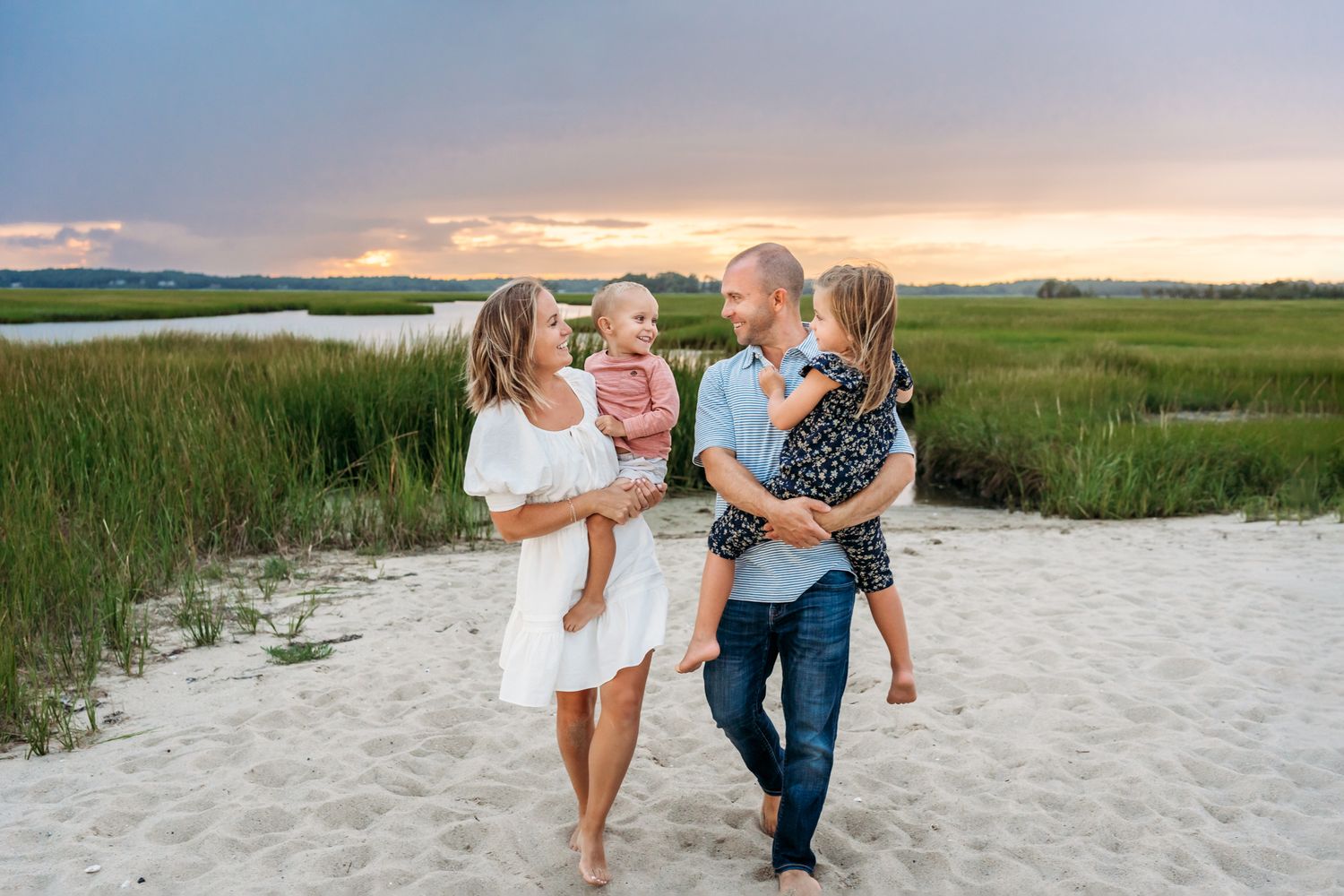 A cheerful group enjoying a summer evening walk on a sandy beach at sunset.