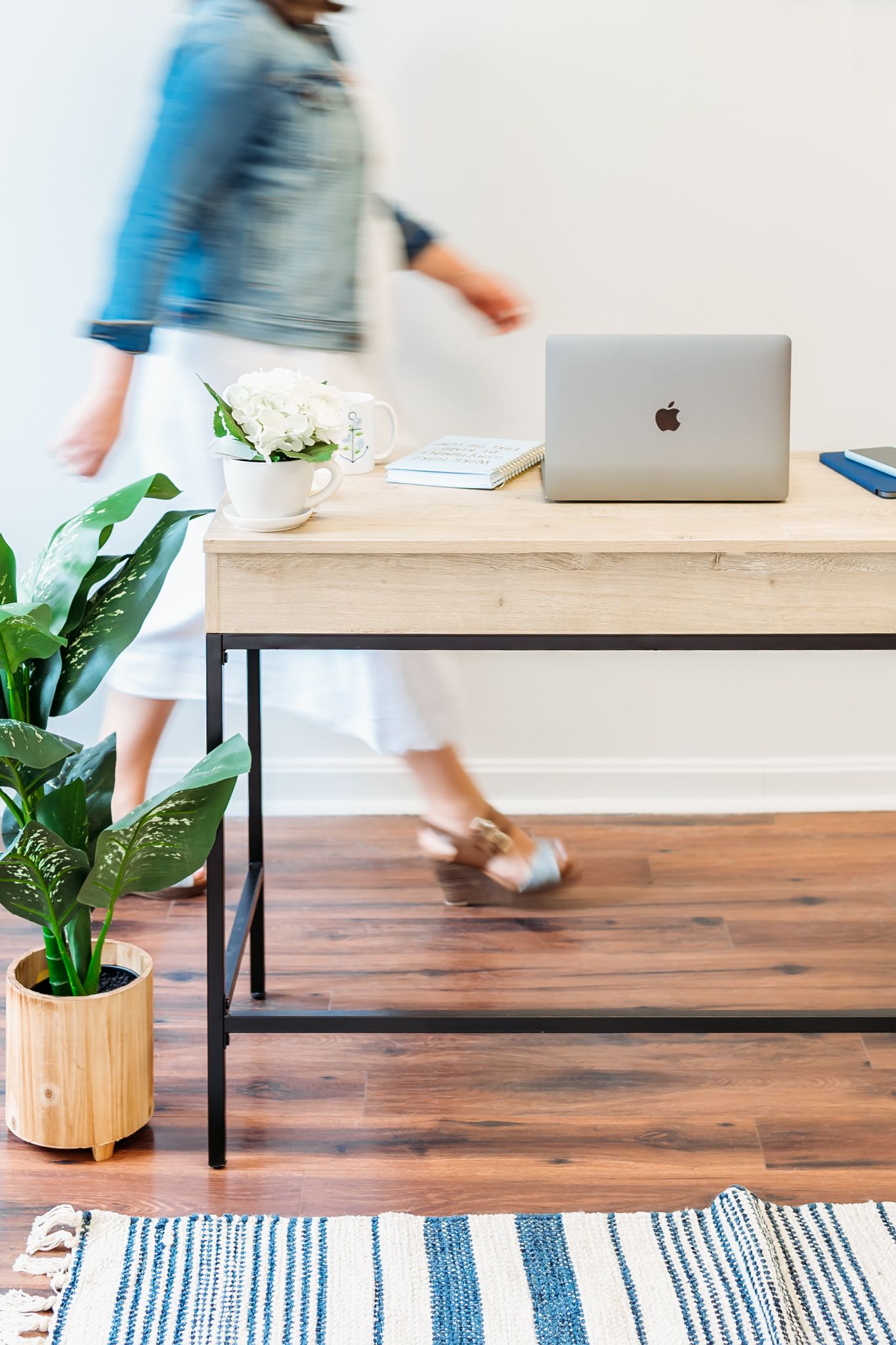 Motion blur captures movement in a modern home office with wooden desk, laptop, and striped area rug.