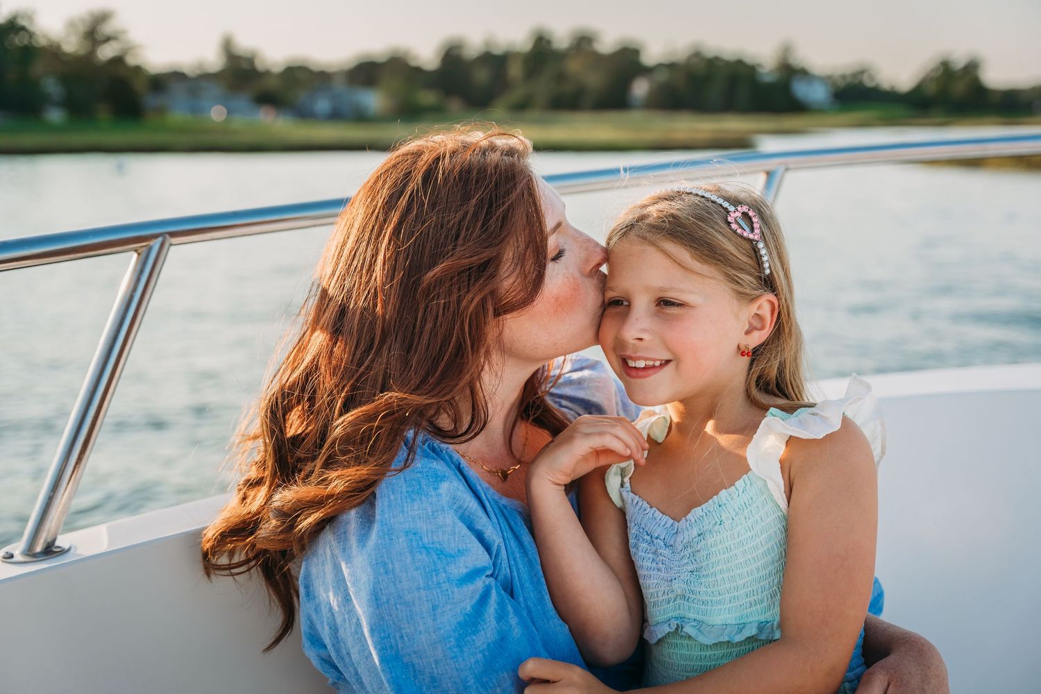 A loving family shares tender moments together on a boat during a summer day on the water.
