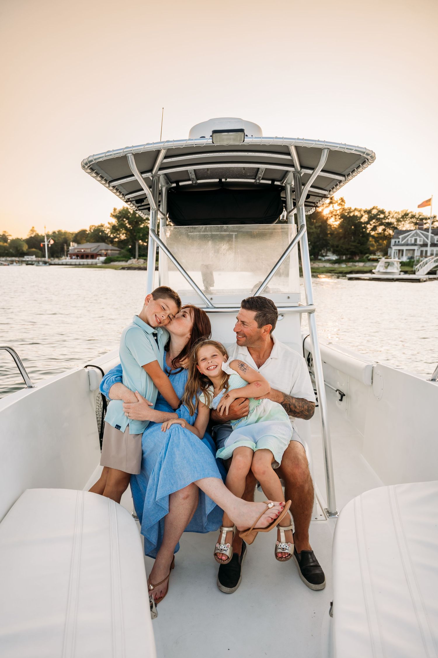 A group enjoying a relaxing afternoon together on a white boat deck overlooking the water at sunset.