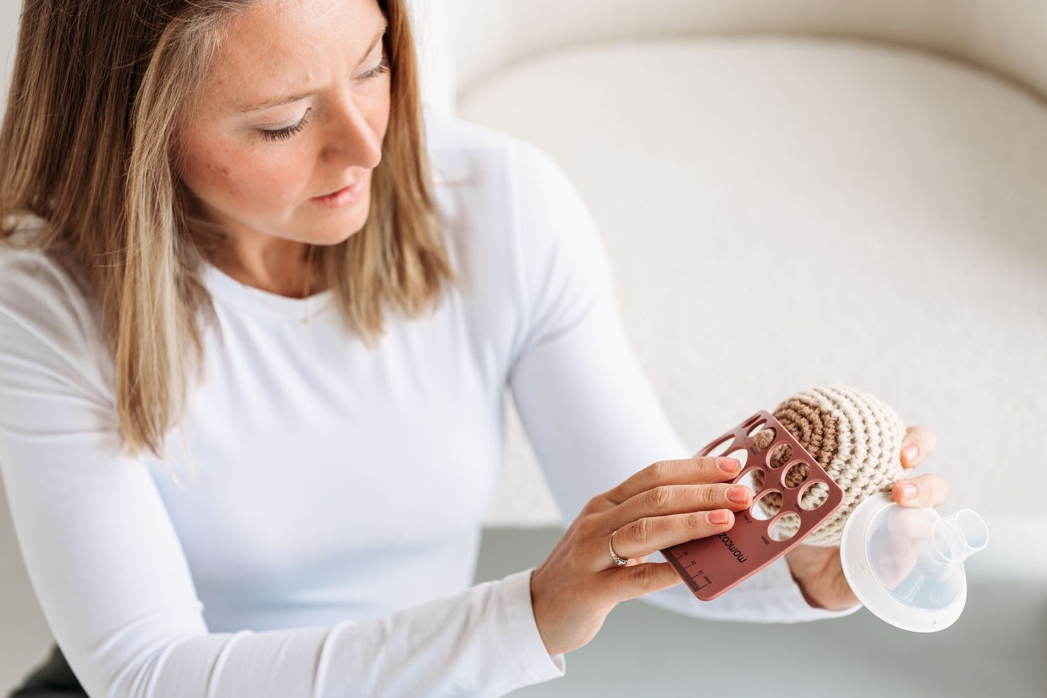 Person in white long sleeve shirt examining and holding a large decorative seashell in their hands.