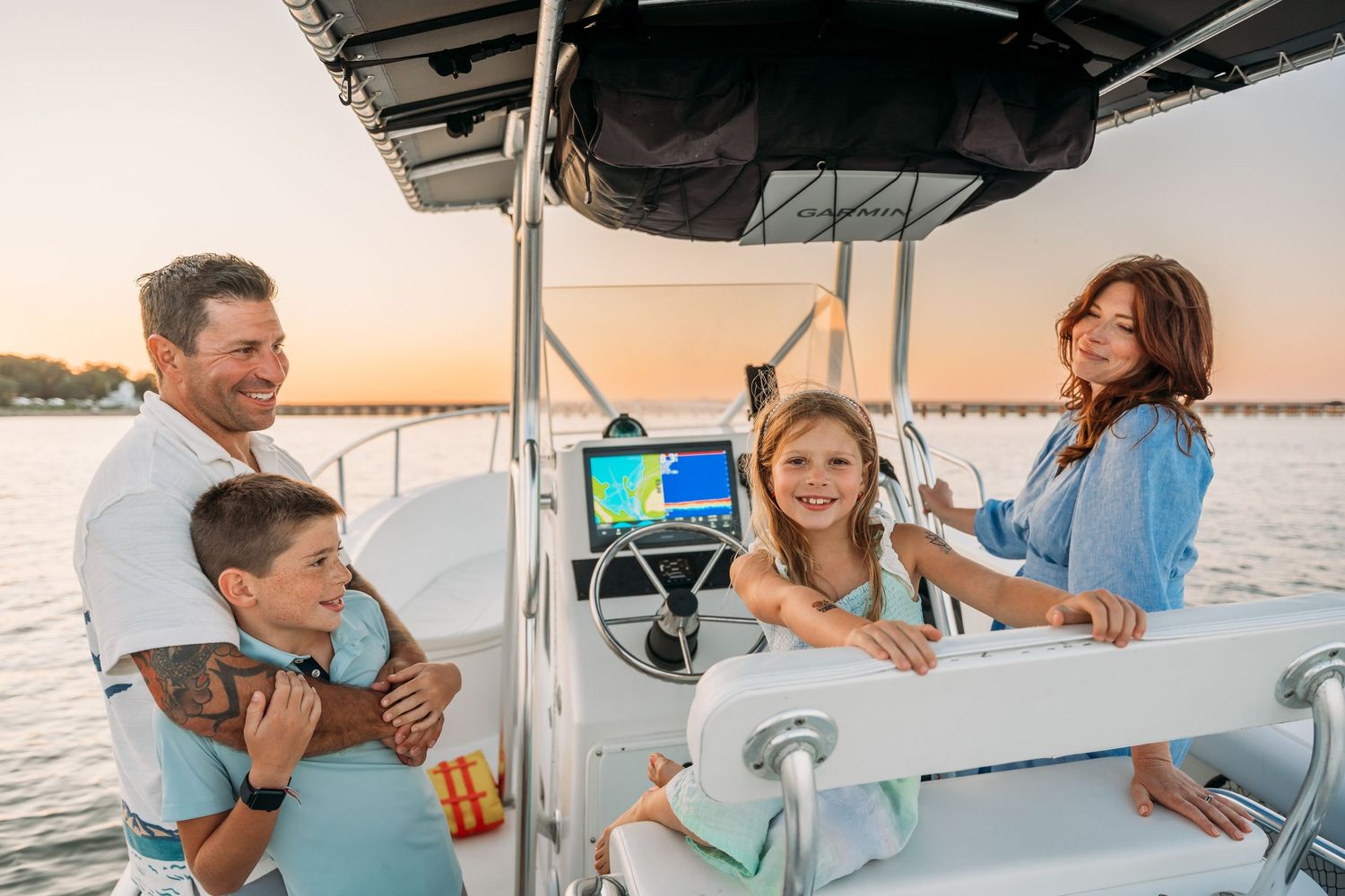 A group enjoys drinks and conversation while sailing on a boat during sunset on the water.