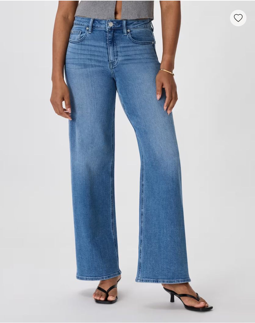 Woman wearing medium wash wide-leg jeans with a high rise, paired with black strappy heeled sandals.