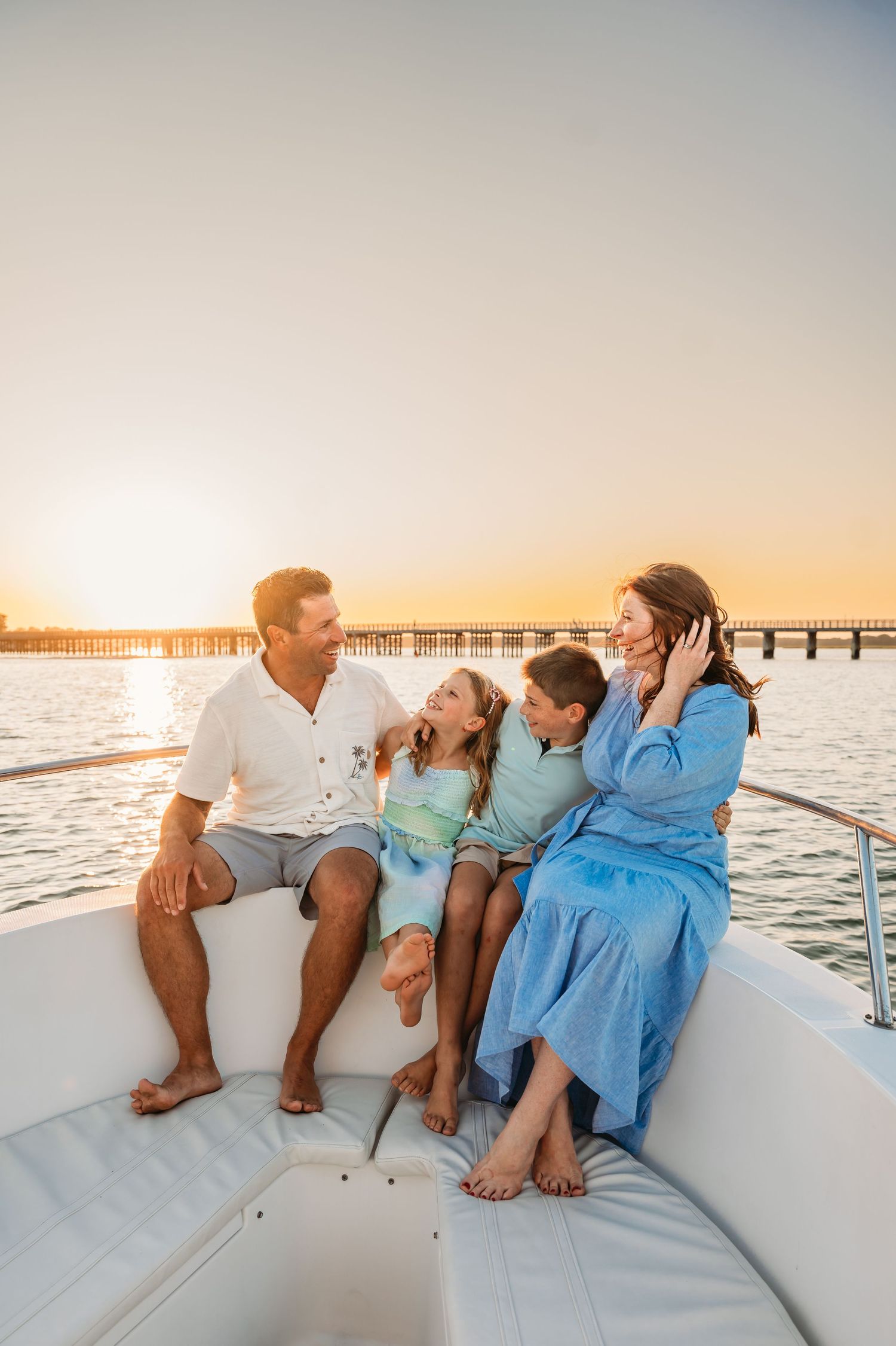 Family enjoying a sunset boat ride together along a pier with golden sunlight reflecting on calm waters.
