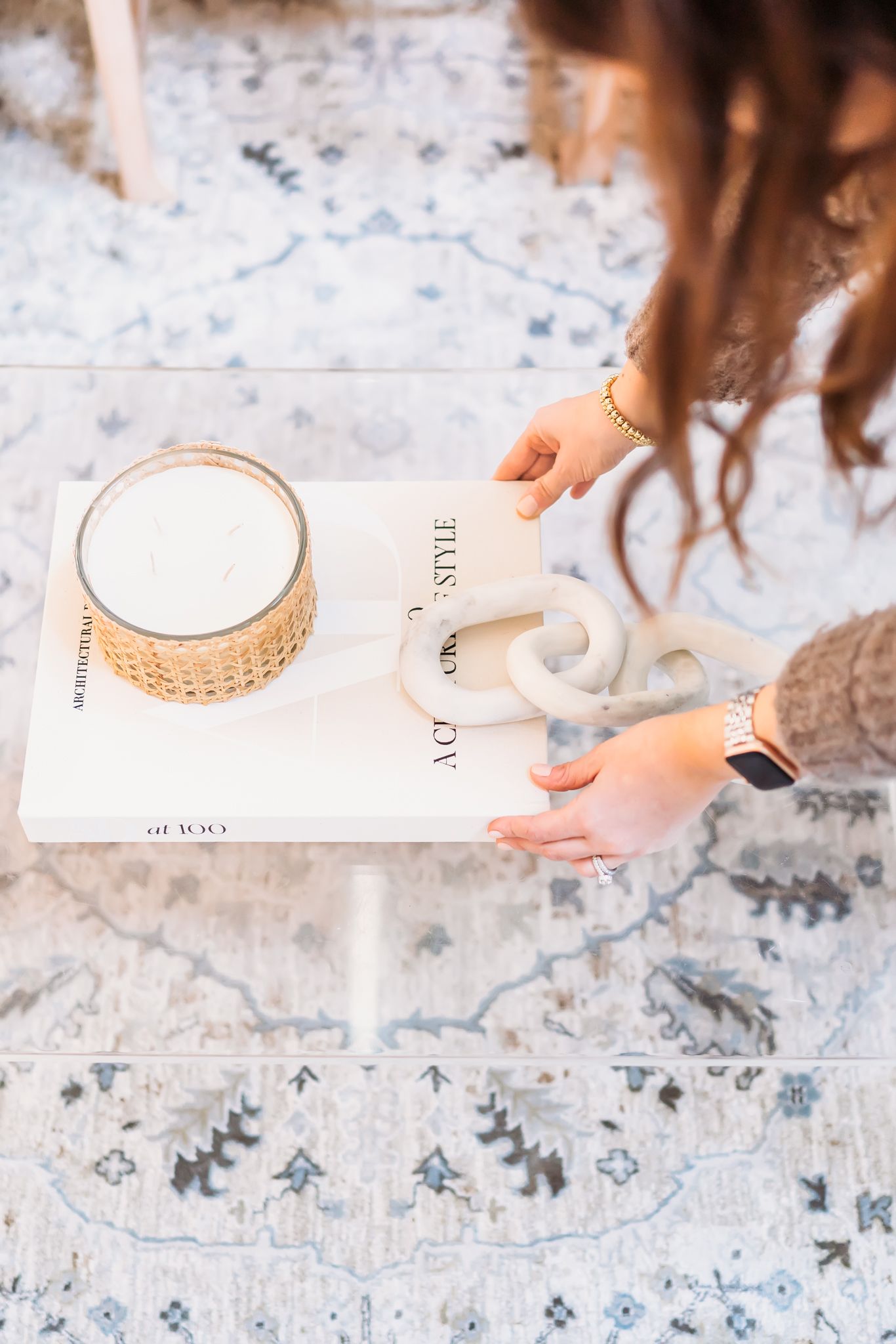 Hands holding a white ceramic coffee cup against a marble surface with delicate blue floral patterns.