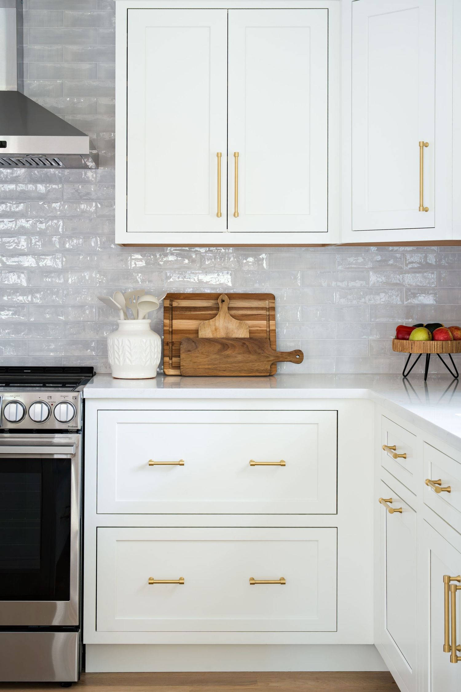 Modern white kitchen cabinets with brass hardware and gray subway tile backsplash feature clean lines and wooden accents.