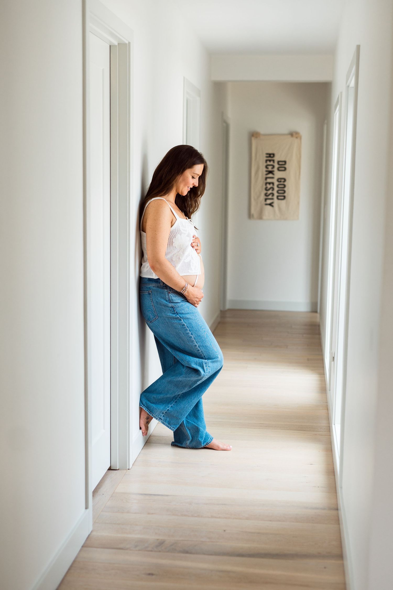 A series of photos showing a person in blue jeans sitting alone in a minimalist white hallway.