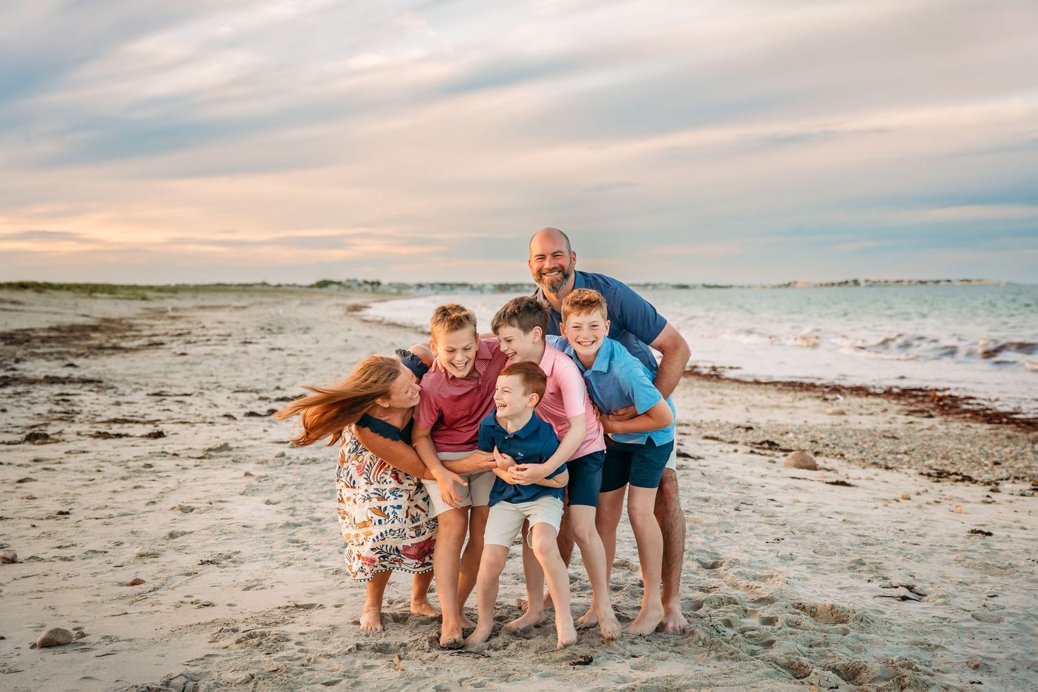 A group of people enjoy a playful moment together on a sandy beach at sunset.