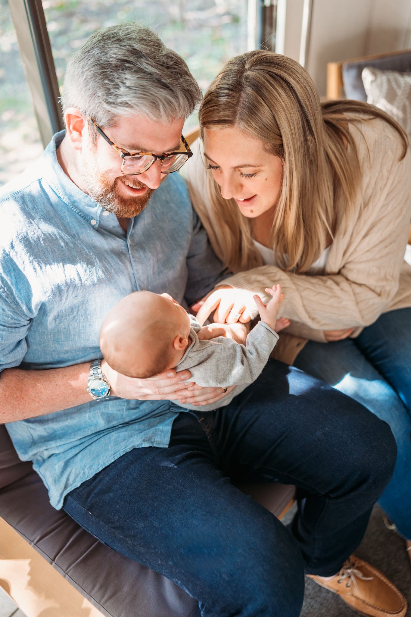 A couple shares a tender moment with their baby while sitting together on a couch.