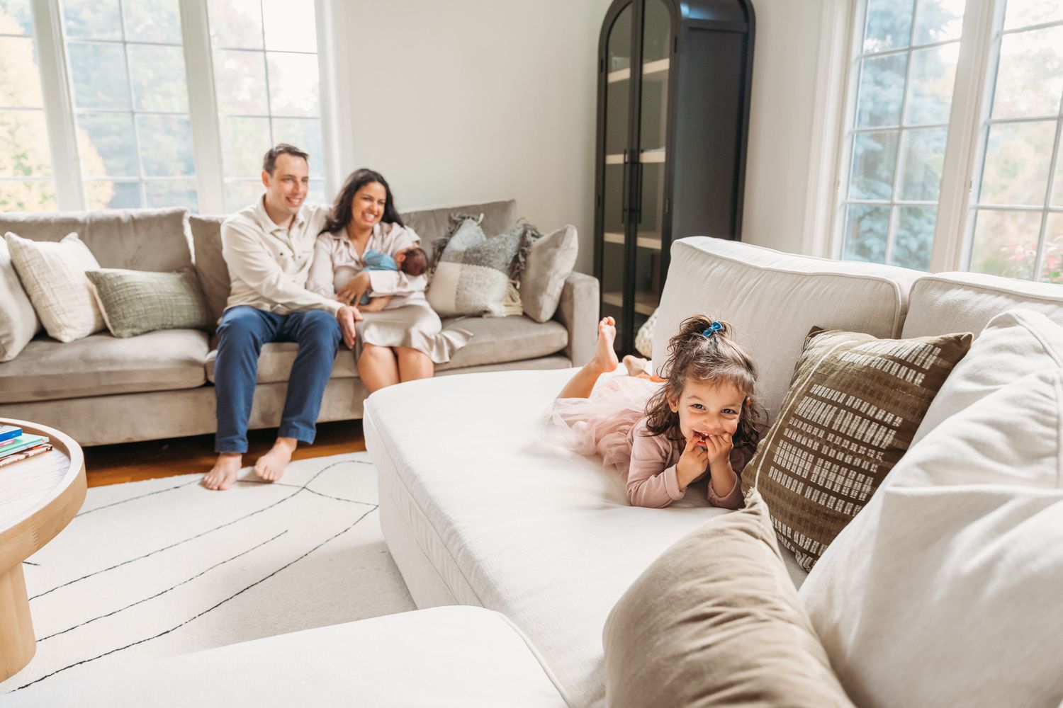A couple relaxes together on a comfortable gray couch in a bright, modern living room.