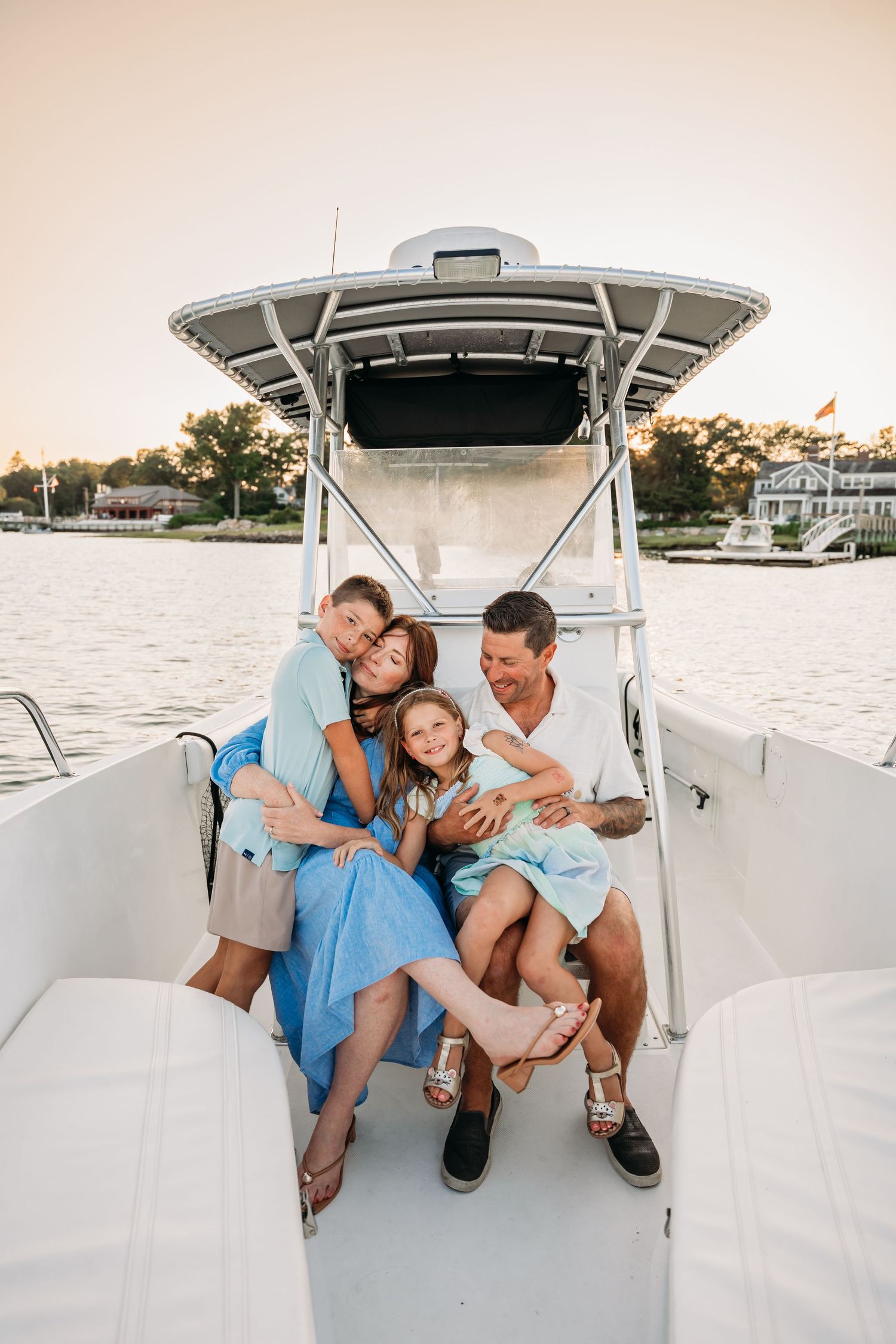 A family relaxes together on a white boat during a sunset cruise along the waterfront.