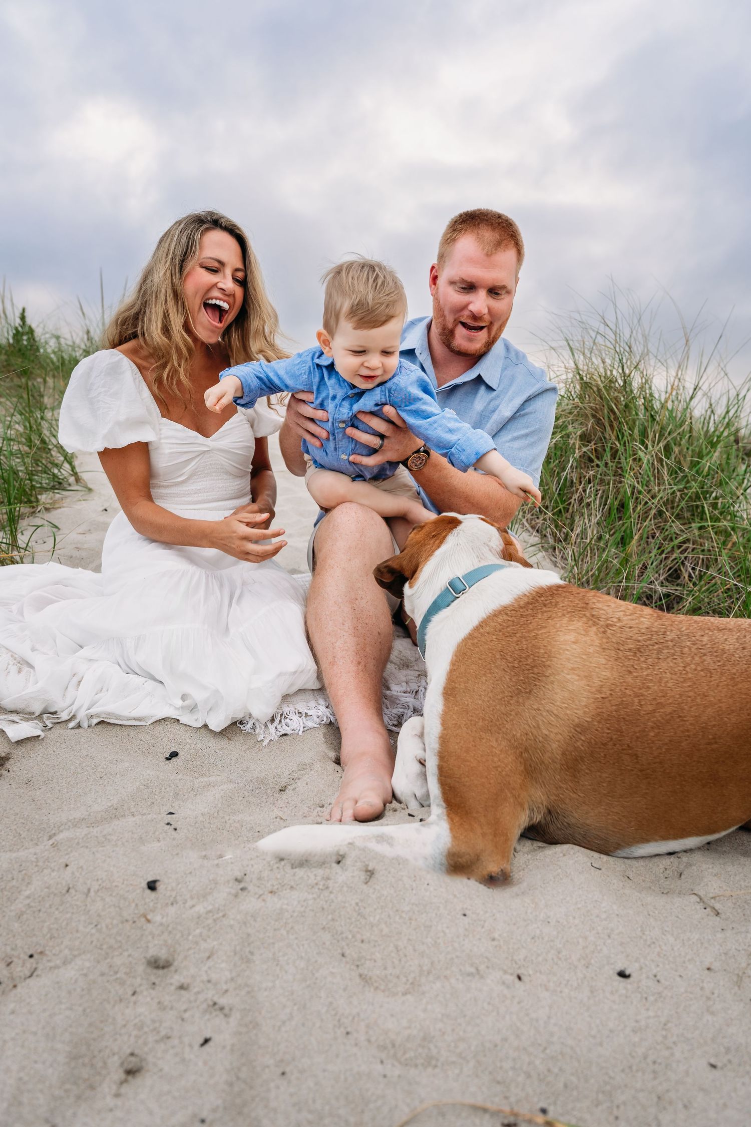 Family and dog having fun together on a sandy beach during a casual outdoor photo session.